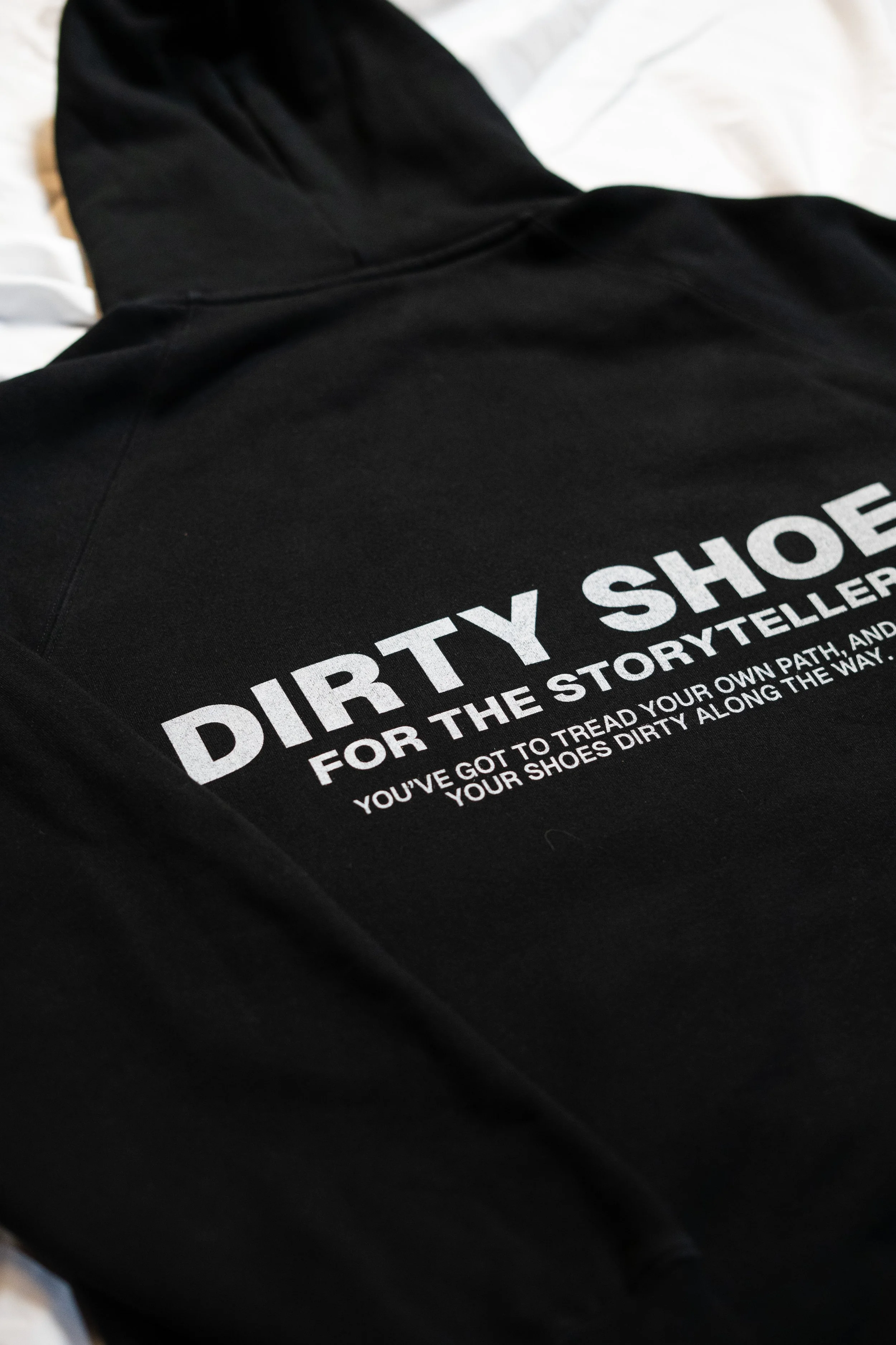 Black hoodie with 'DIRTY SHOES FOR THE STORYTELLERS' printed in white text.