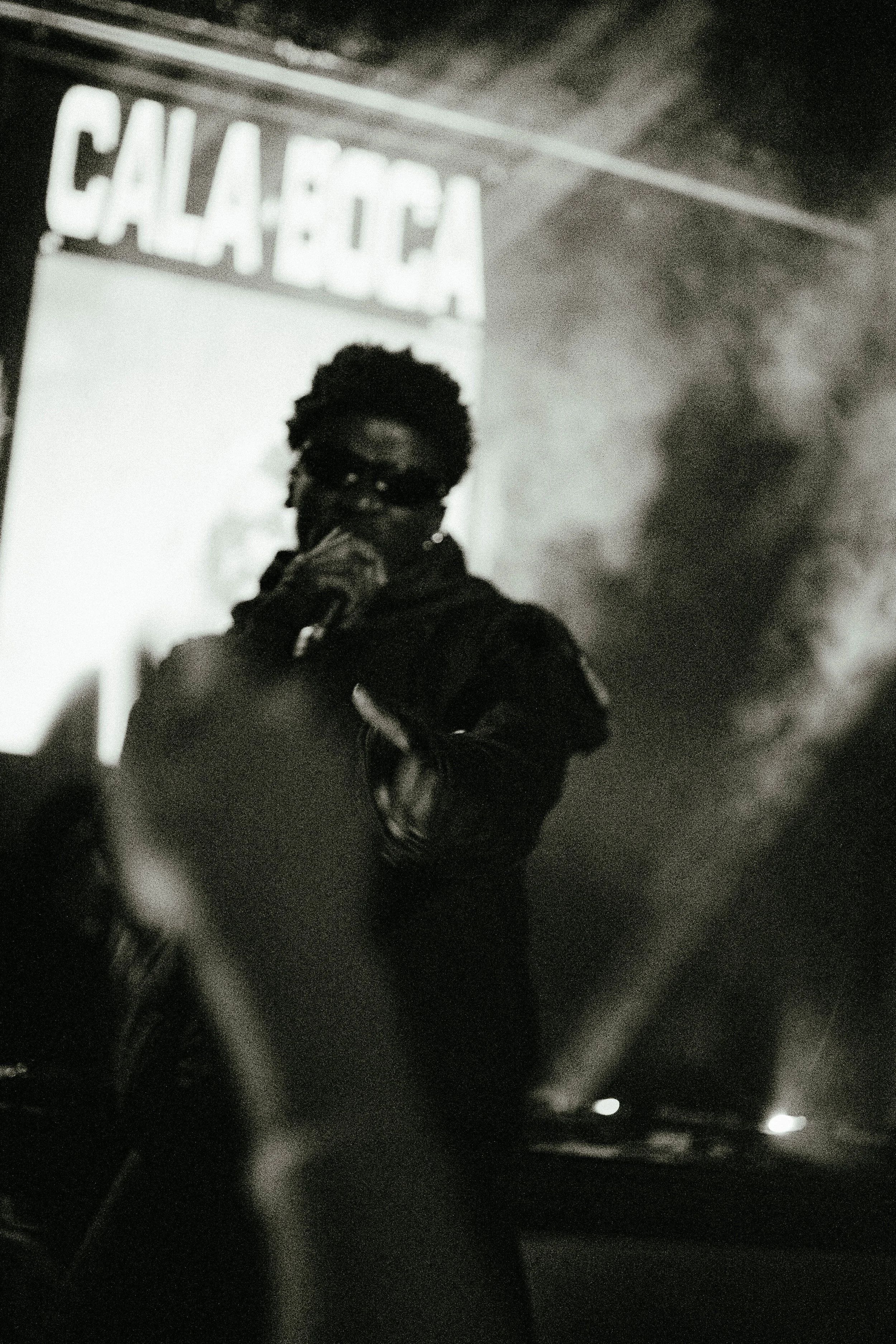 A person with glasses singing into a microphone on stage at a CALABOGA event.