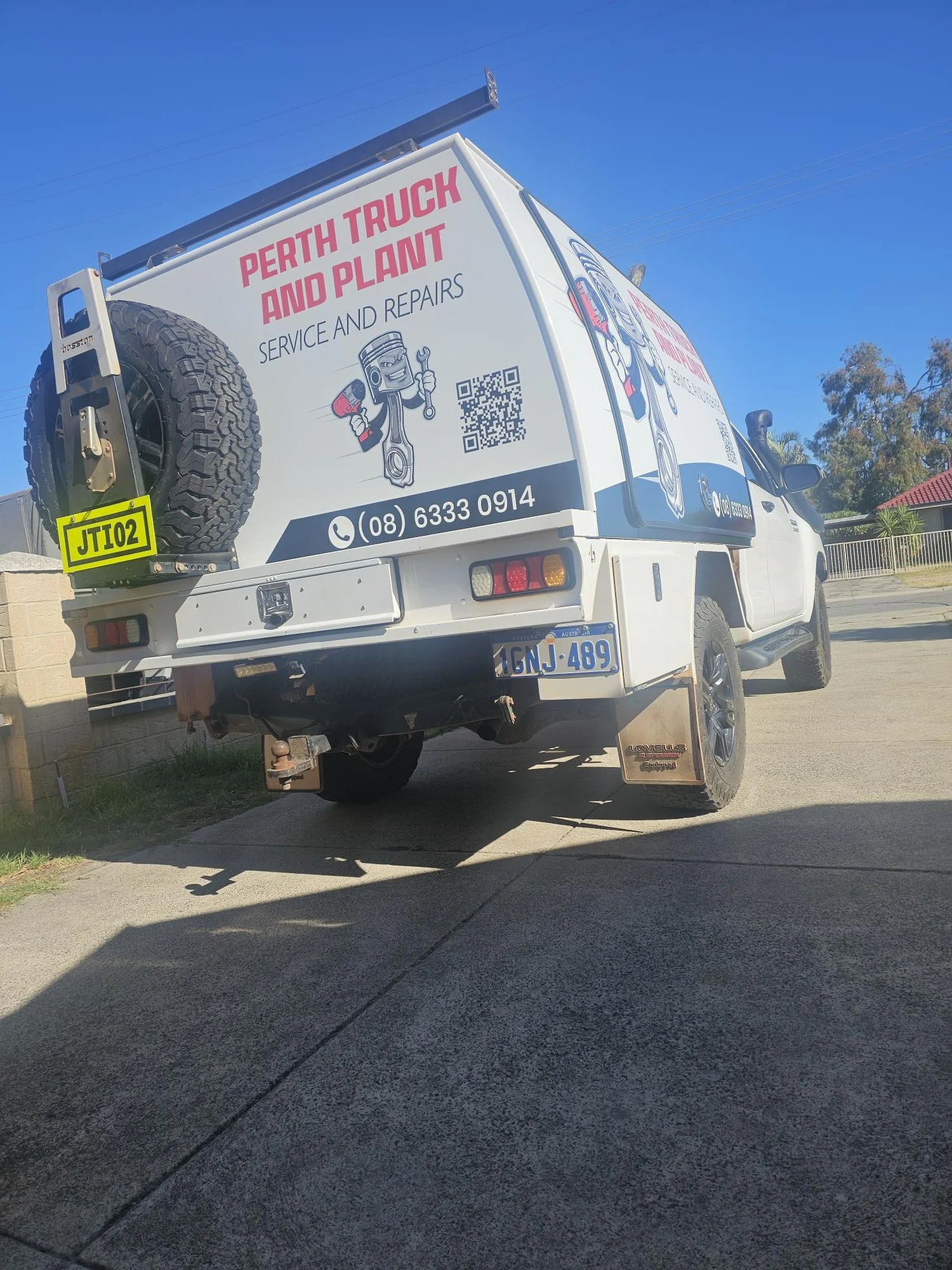Service van for Perth Truck and Plant with contact number, QR code, and cartoon graphics of tools.