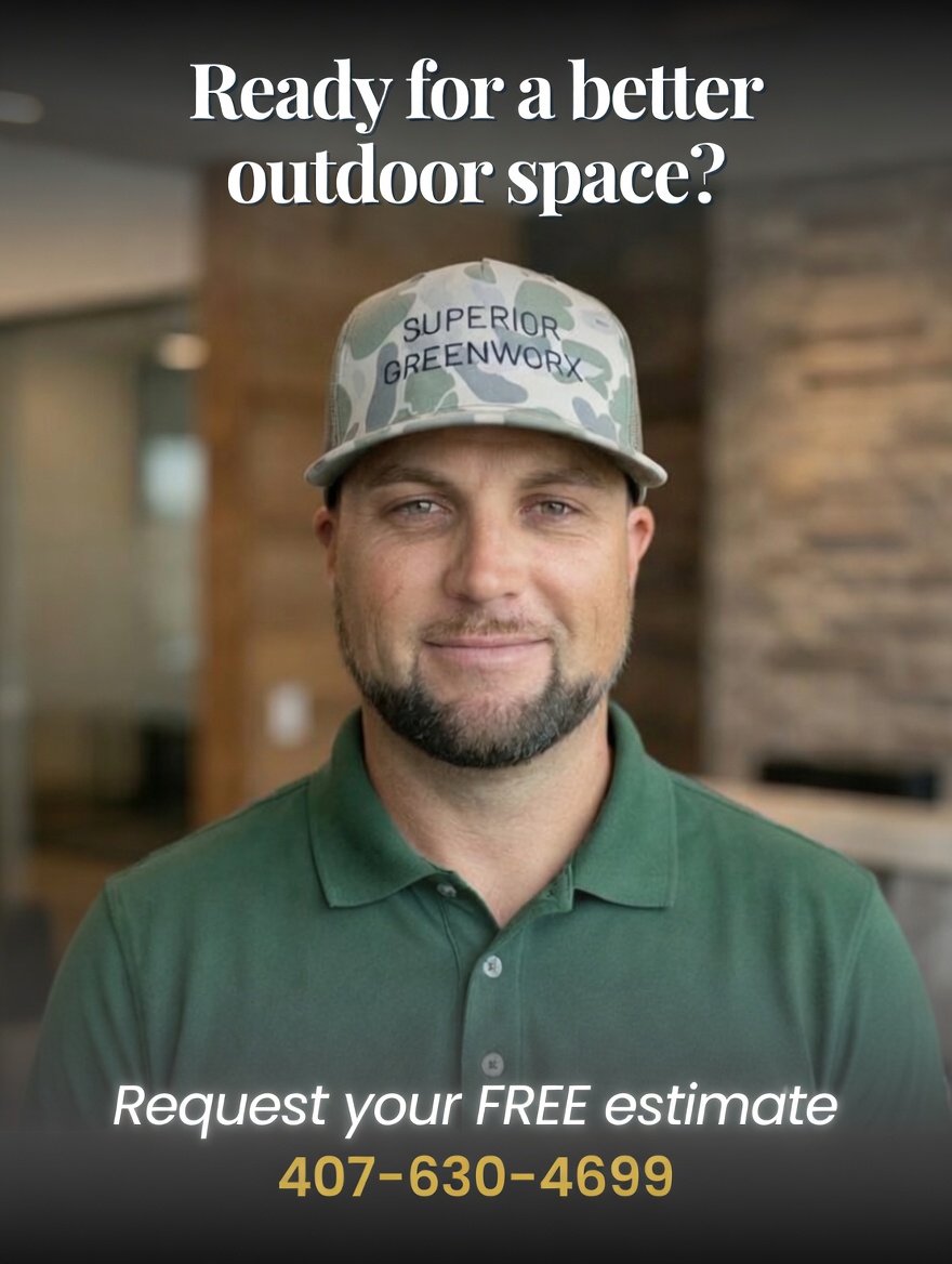 A man wearing a green polo shirt and a camouflage cap that says "Superior Greenworx" is smiling indoors with a blurred background of wood and glass. Text overlay reads: "Ready for a better outdoor space? Request your FREE estimate 407-630-4699."