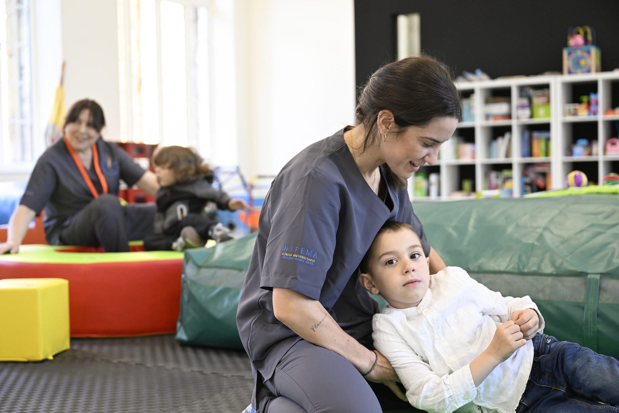 Dos terapeutas jugando con niños en un ambiente de terapia física para niños.