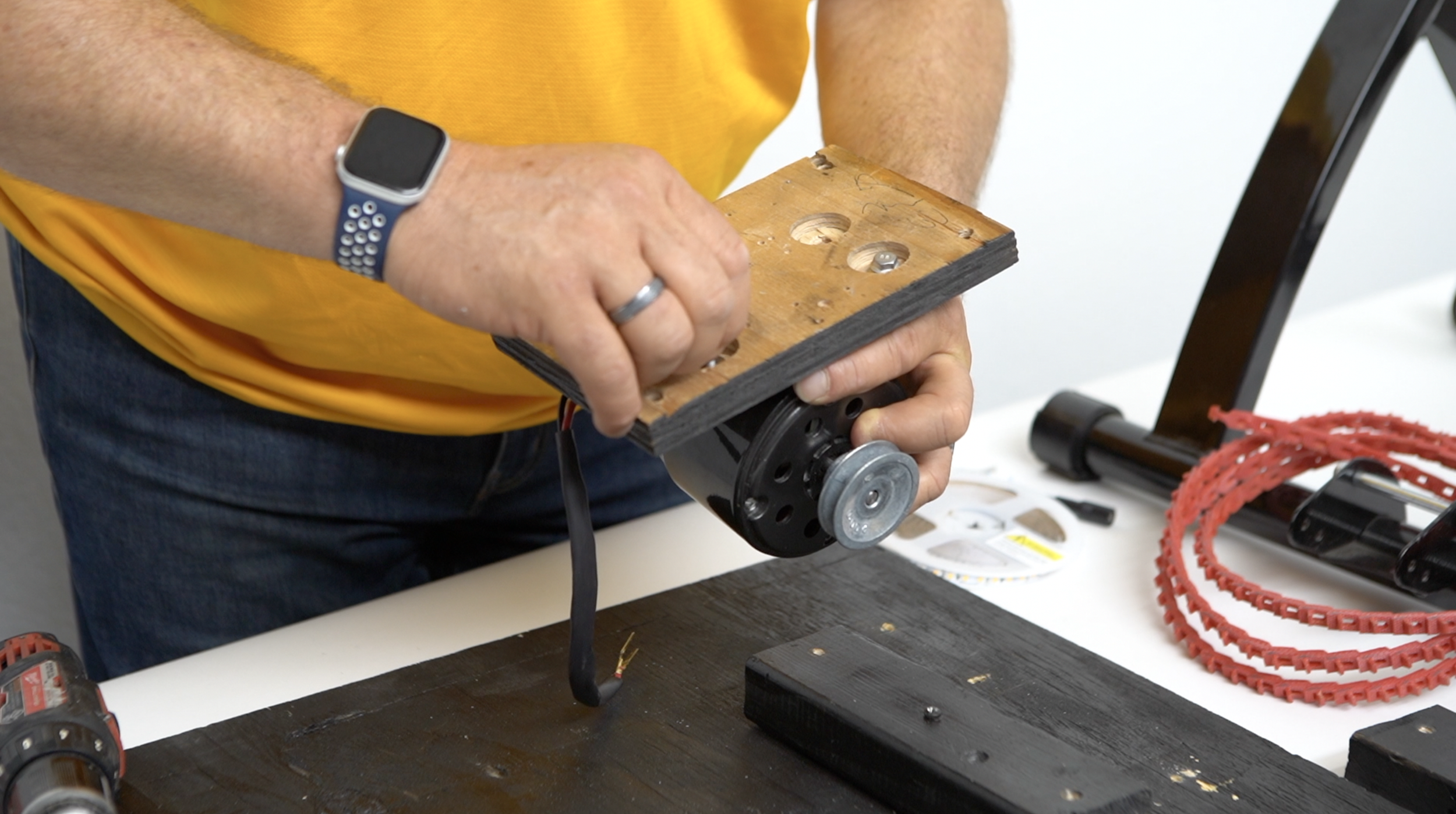 Man tightening the screws of a bicycle generator to a small piece of plywood