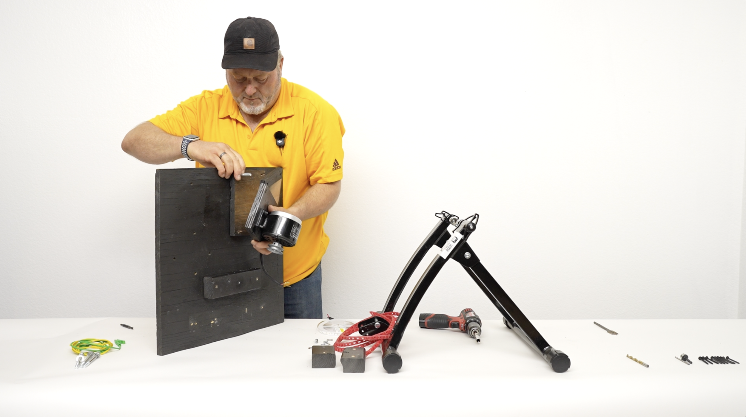 Man tightening the screws of a bicycle generator to a small piece of plywood
