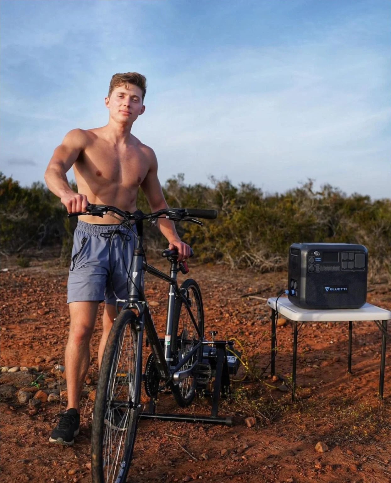 man charges a portable power battery station by pedaling a 500 watt bicycle generator in the desert of arizona