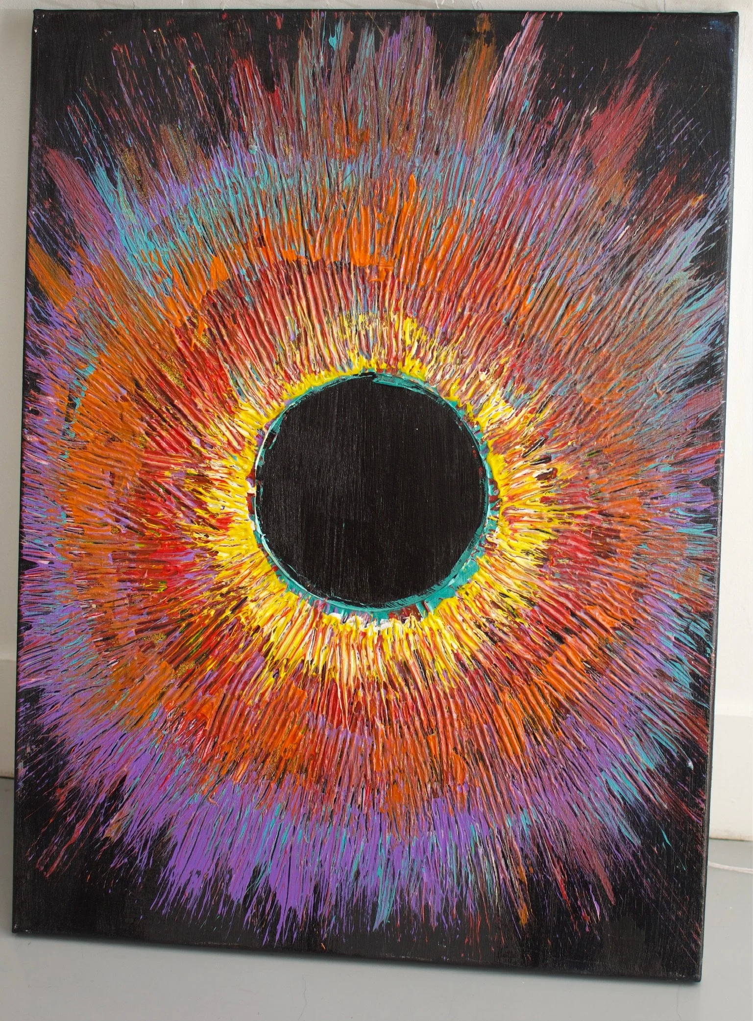 Abstract circular painting with vibrant colors radiating from a black center, featuring orange, yellow, red, purple, and blue hues.