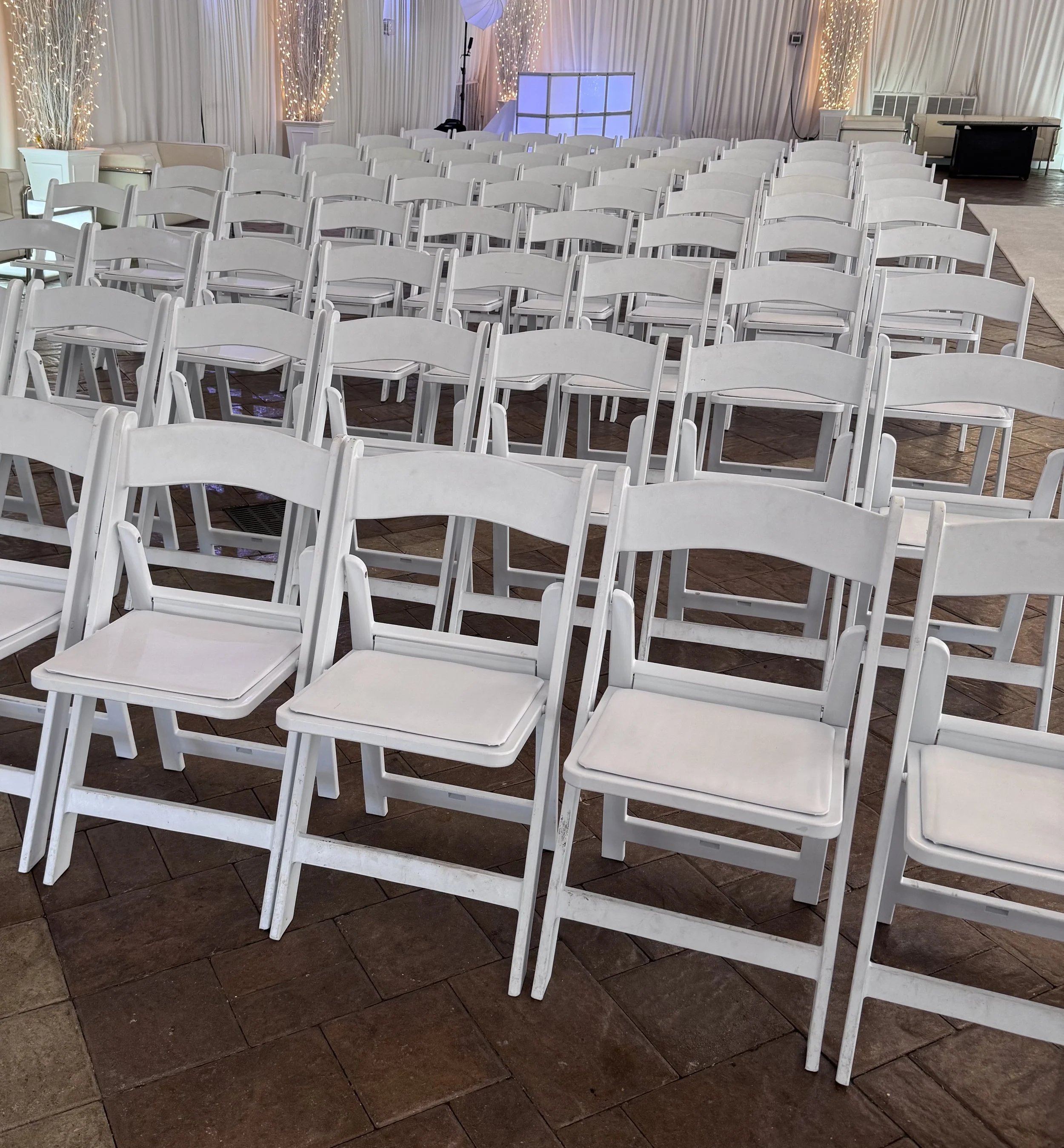 White resin chairs setup for a formal event at a wedding venue.