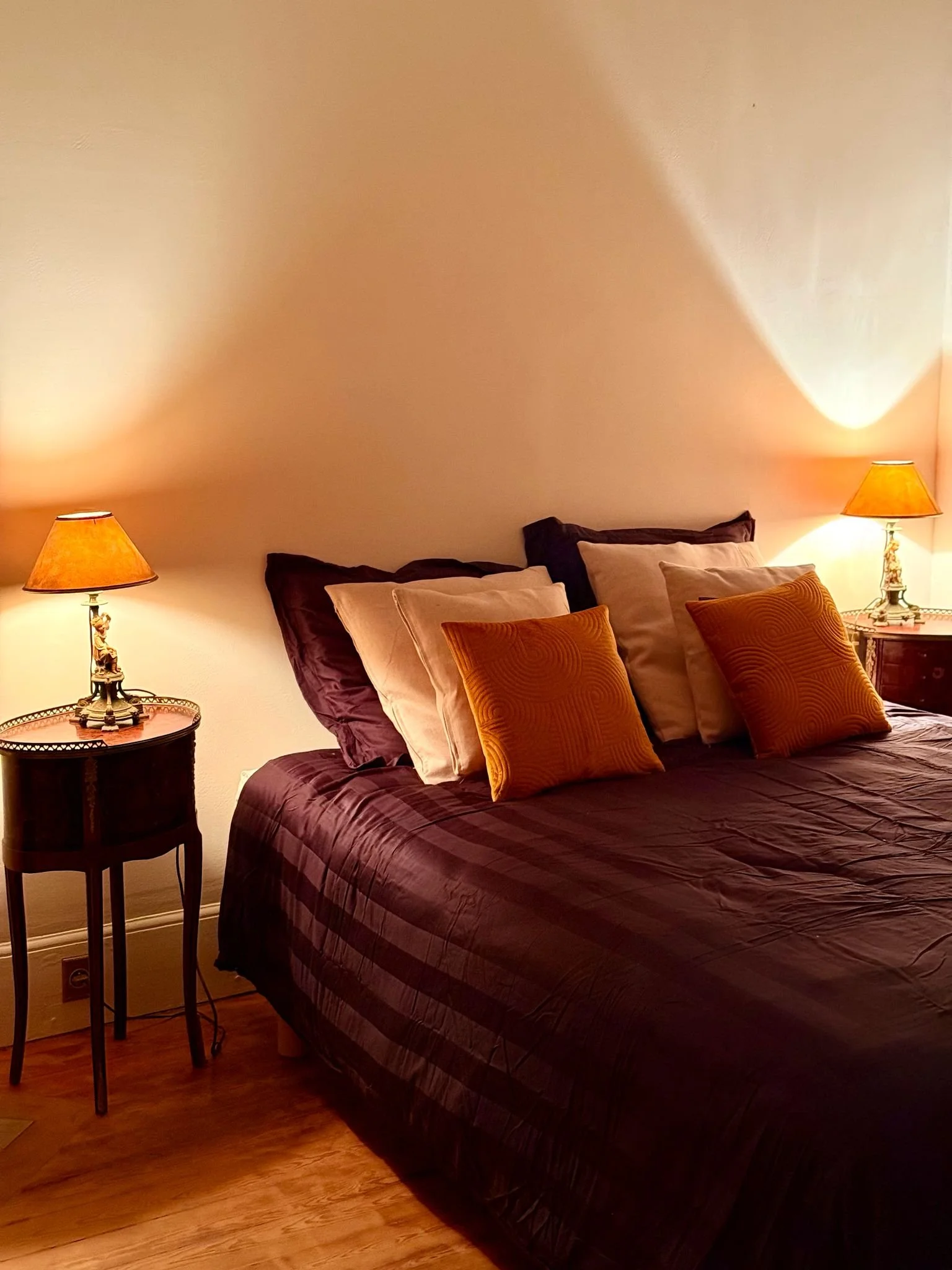 Chambre avec un lit double, draps foncés, coussins orange et beiges, tables de chevet avec lampes allumées.séminaires au vert. Hôtel près de gisors. Teambuilding