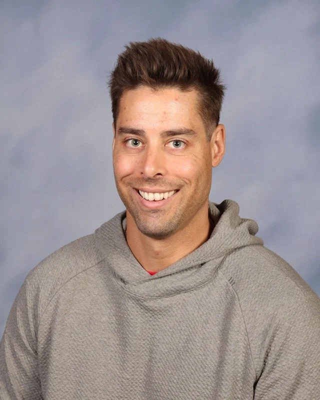 A navy blue shield with a stylized emblem in the center consisting of crossed lightning bolts, a spear, and a stylized letter C.