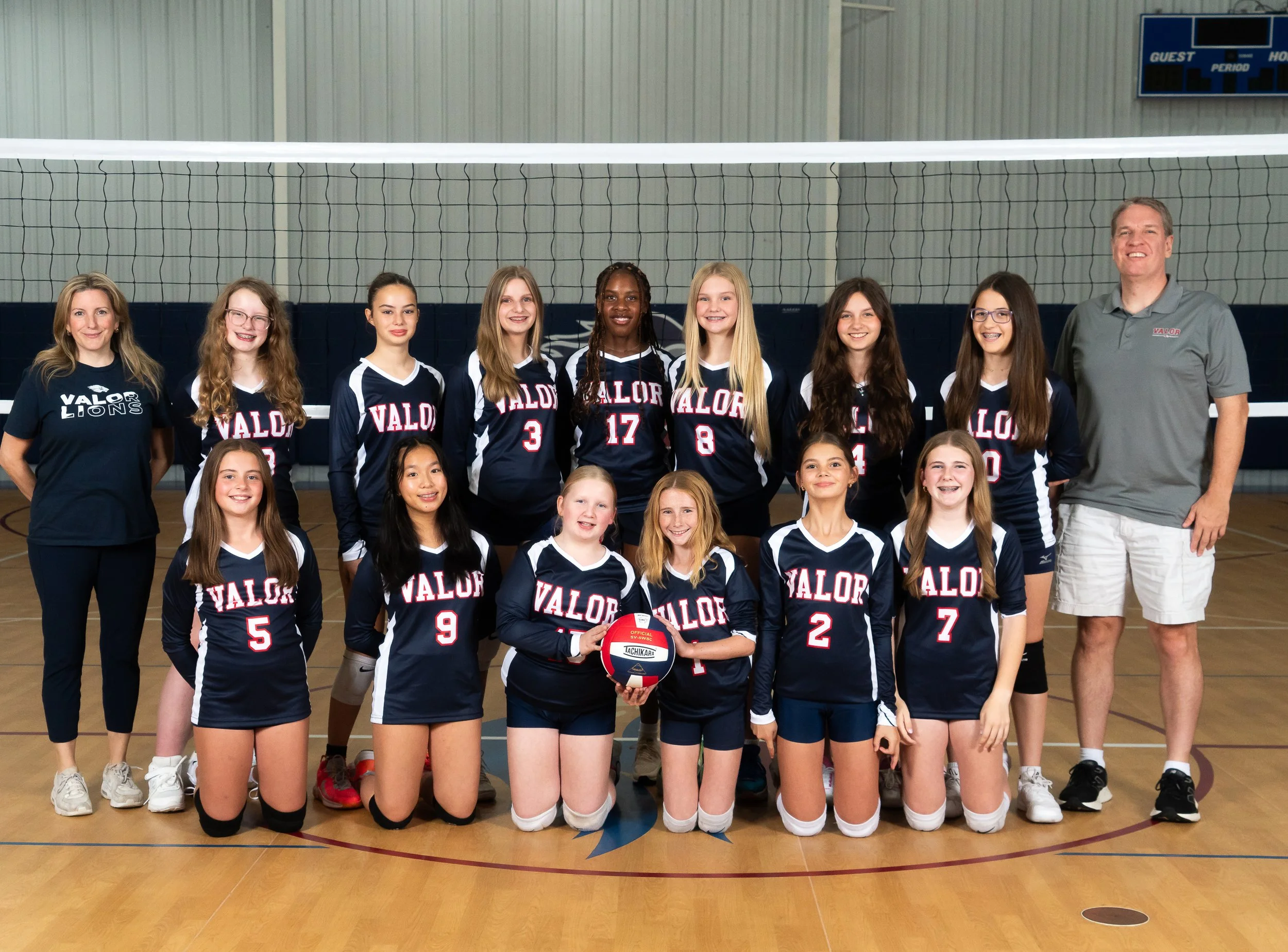 A girls' volleyball team in navy uniforms with