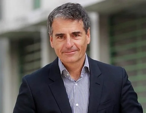 Hombre de traje sonriente en un entorno urbano.