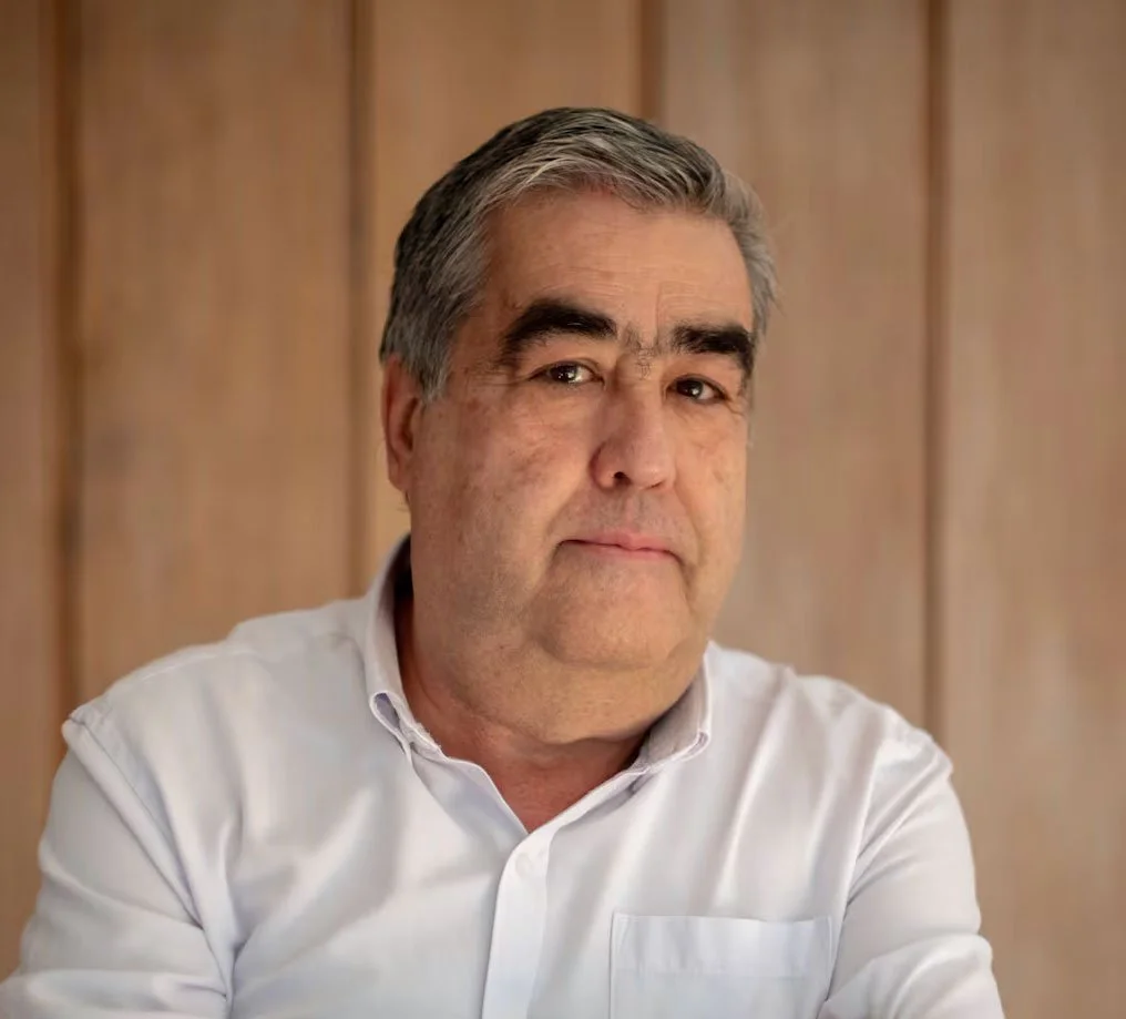 Hombre mayor con camisa blanca, fondo de madera.