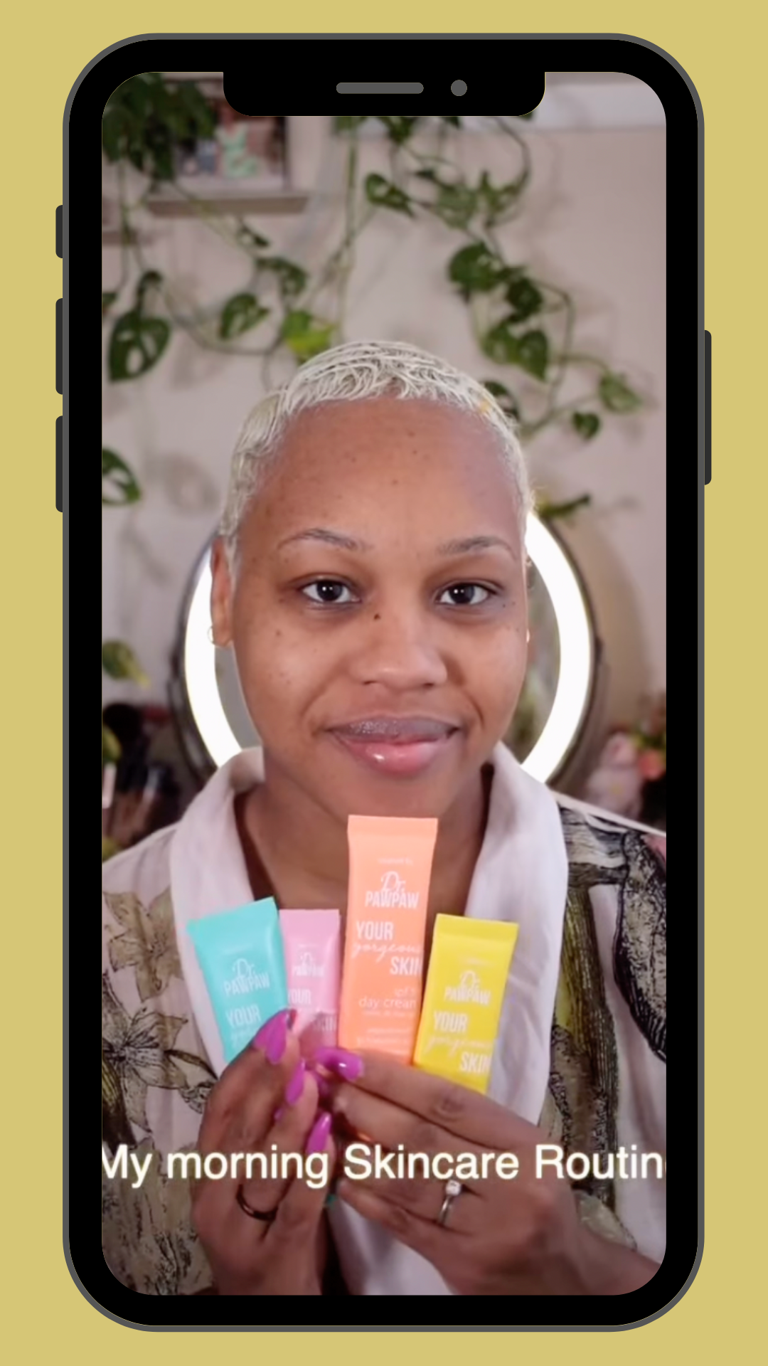A woman smiling and holding four skincare products with the caption "My morning Skincare Routine" on a phone screen.