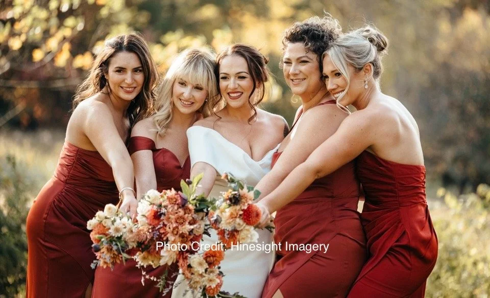 Group of five women dressed in formal attire at an outdoor wedding