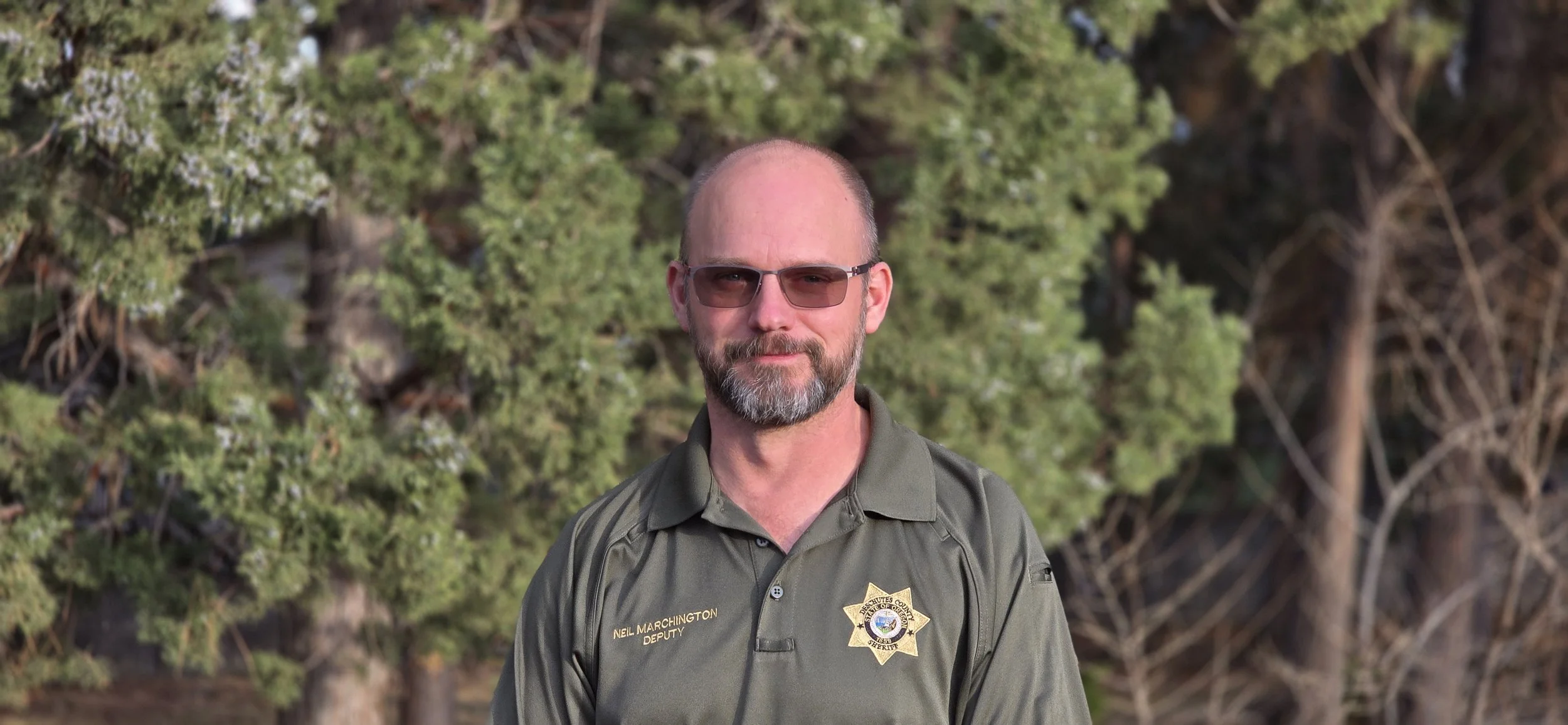 Man with glassesin sheriff's deputy polo shirt