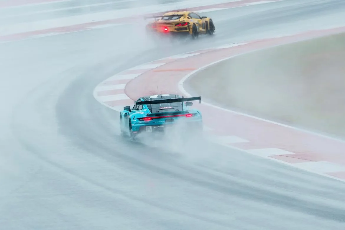 Blue and yellow sports cars on a very wet track