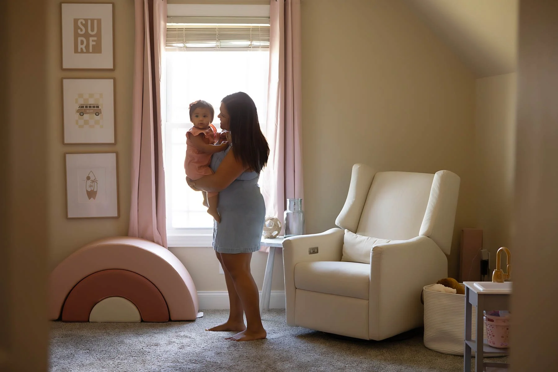 Mom and baby in front of natural window light in a calm nursery, demonstrating peaceful nursery ideas and connection taken by Andria Fontenot