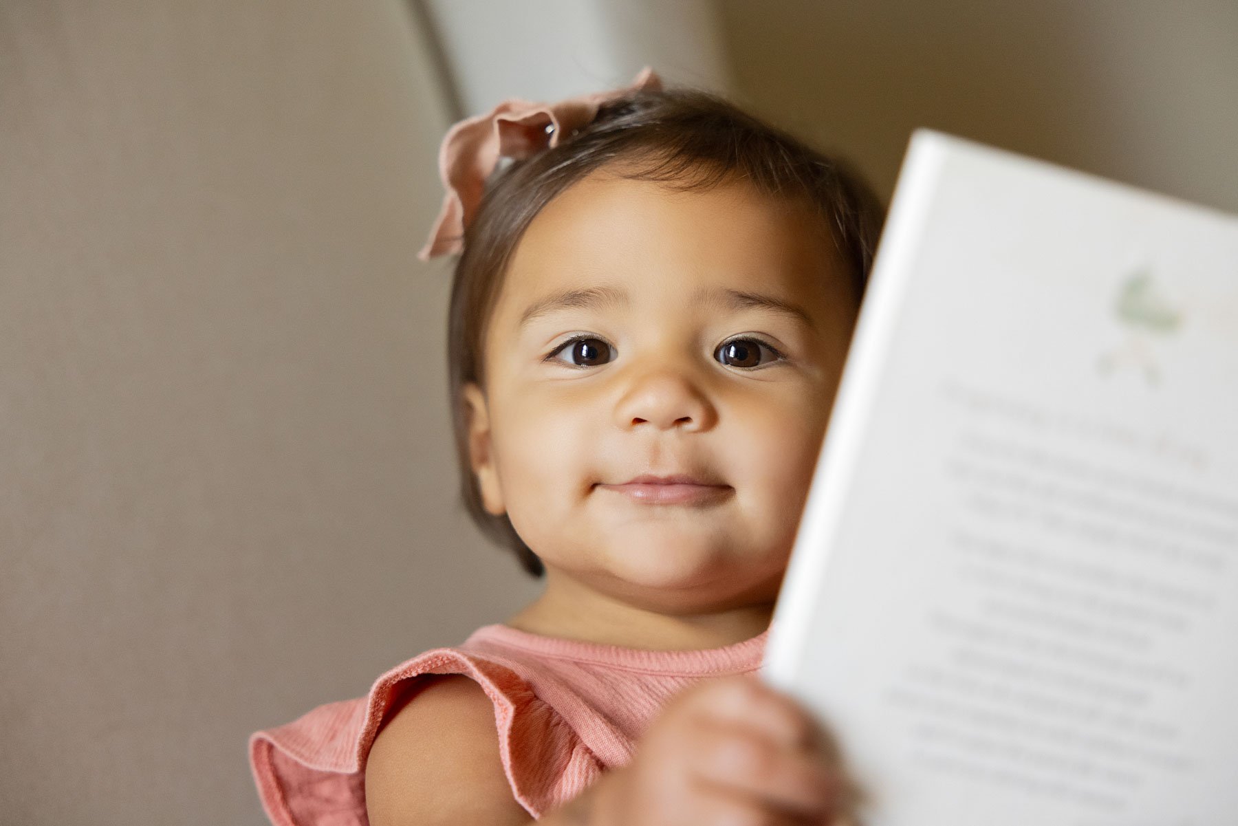 Close-up of baby holding a book in soft natural light, a peaceful nursery idea that supports baby development through contrast.