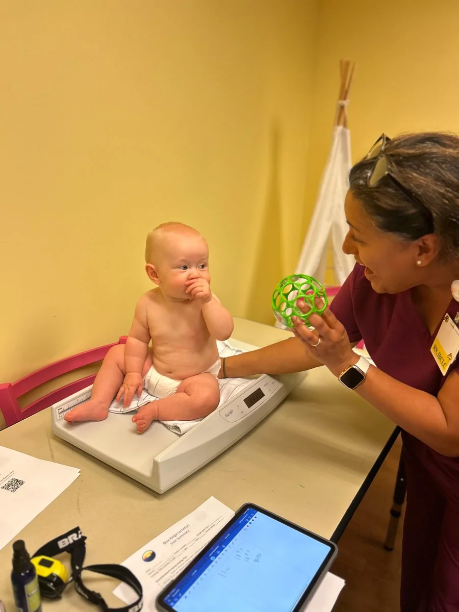A baby sitting on a table looking up at the lactation consultant in Lynchburg, VA.