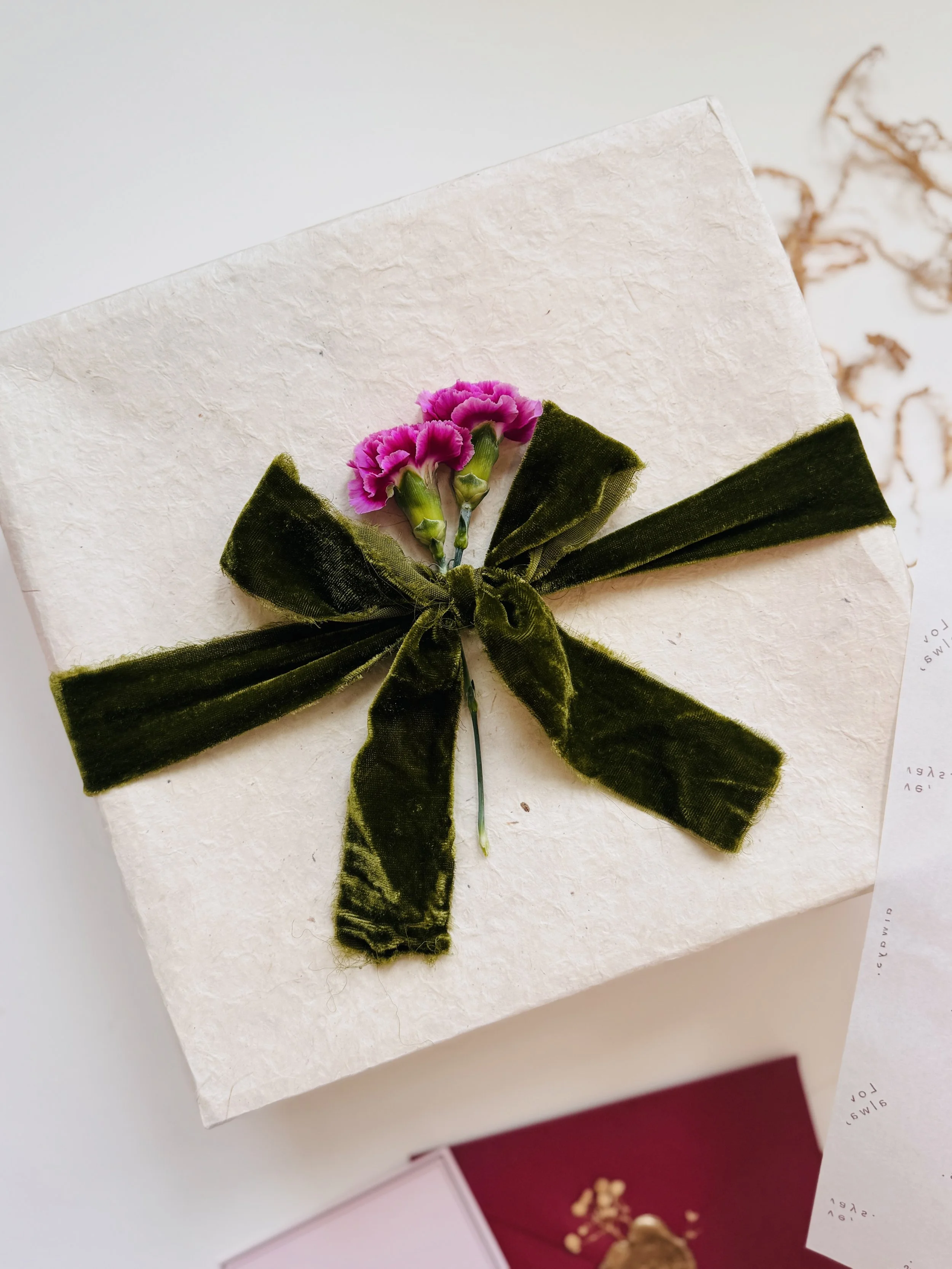 Ivory-textured Diwali gift box tied with olive velvet ribbon and pink carnations — luxury festive packaging by Go Gaga Gifts.