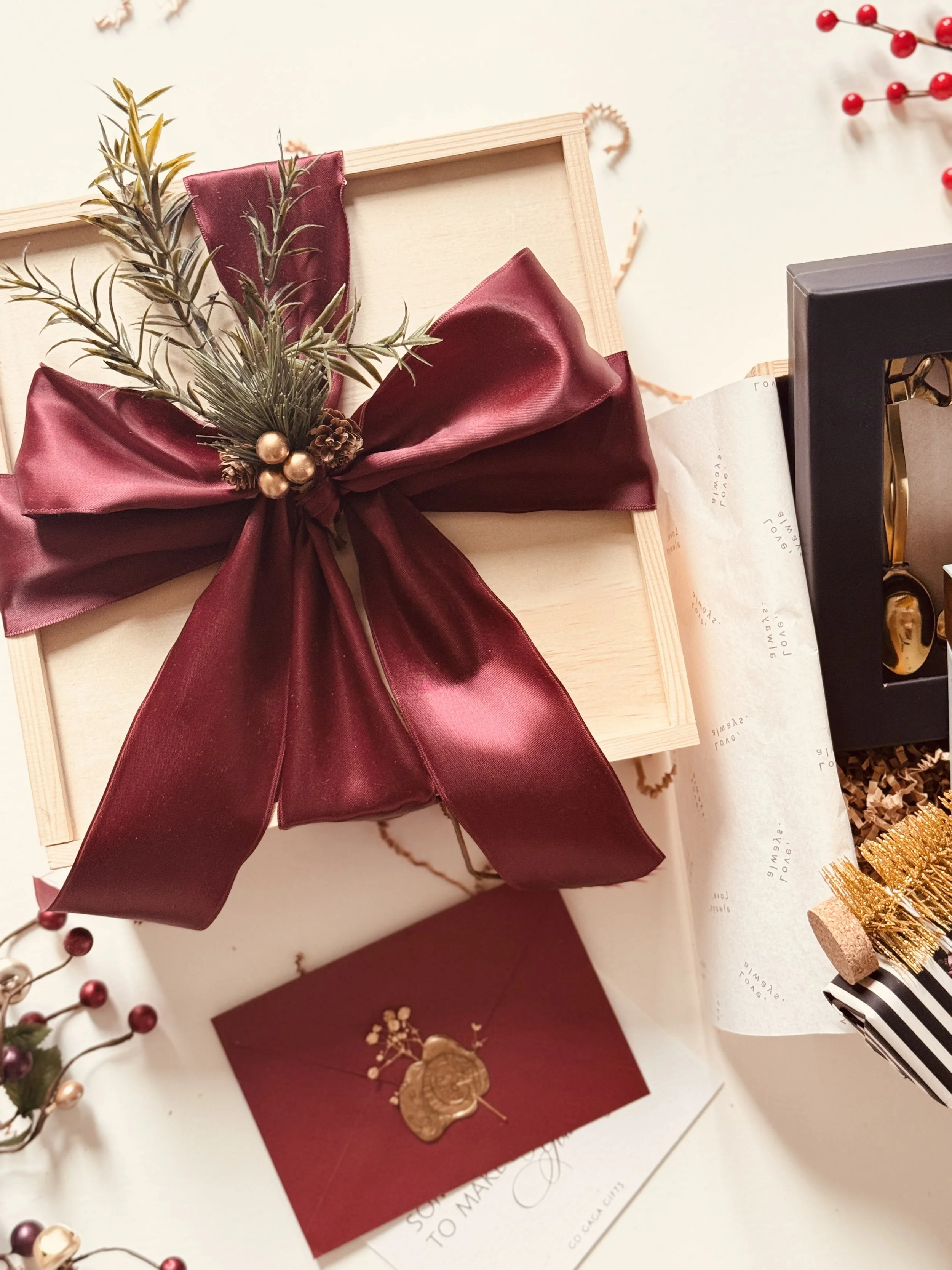 Wooden gift box tied with deep burgundy satin ribbon and festive embellishments