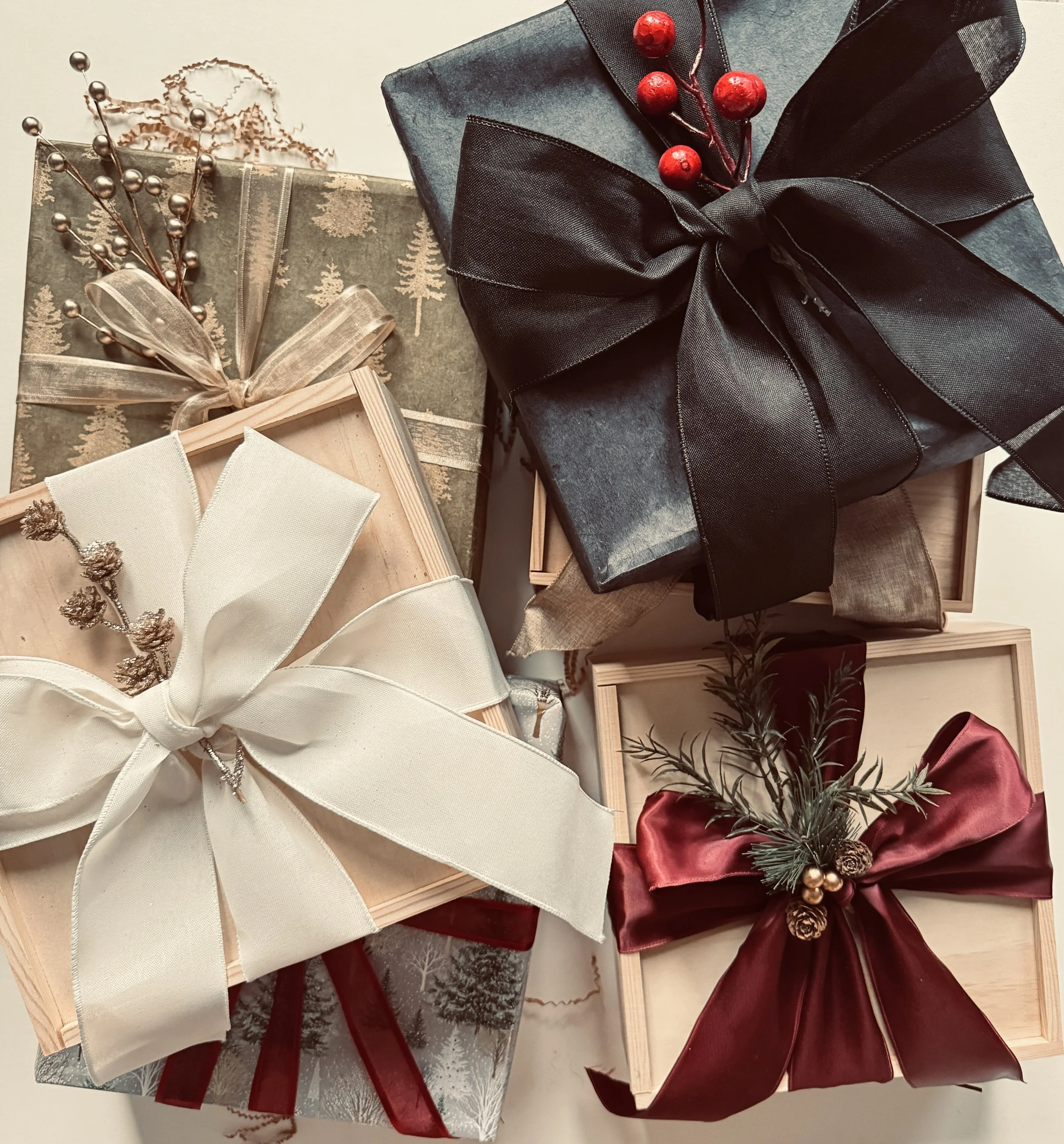 Several wrapped Christmas presents decorated with ribbons and holiday ornaments, including berries, pine branches, and pinecones.