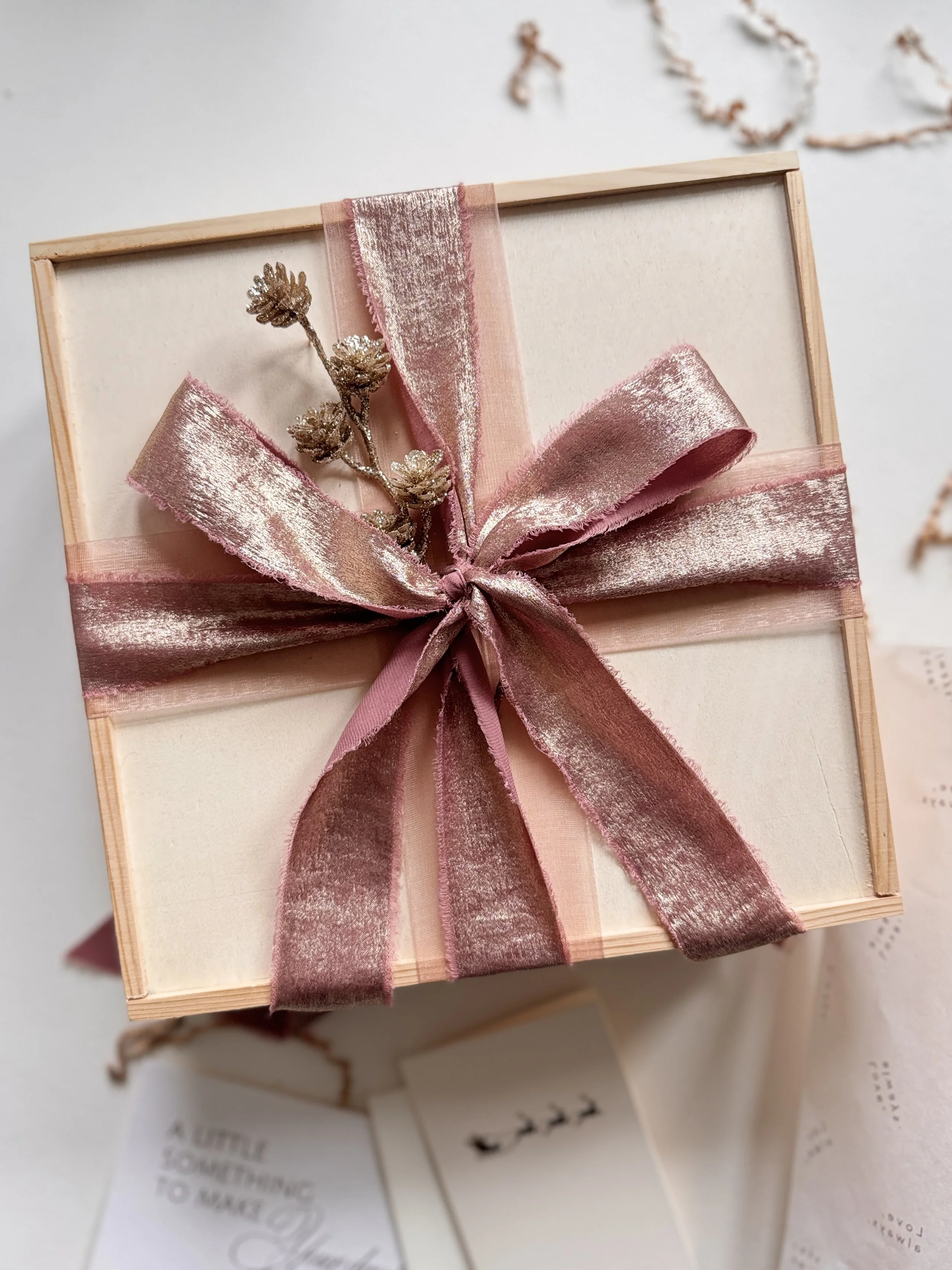 Luxury Christmas gift box for her wrapped in shimmering rose ribbon with gold pinecone accents
