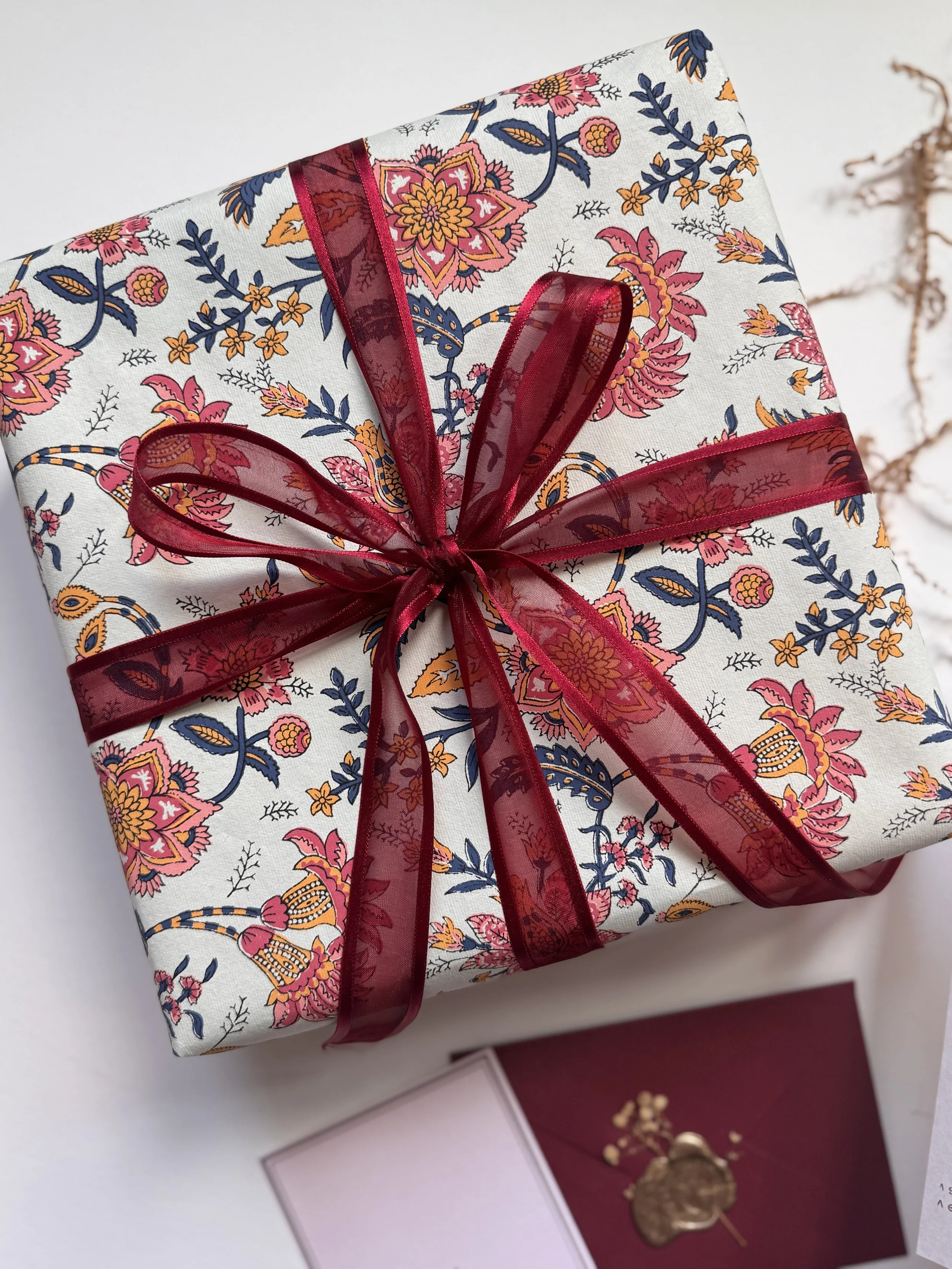Gift box wrapped in floral fabric with maroon ribbon for Diwali