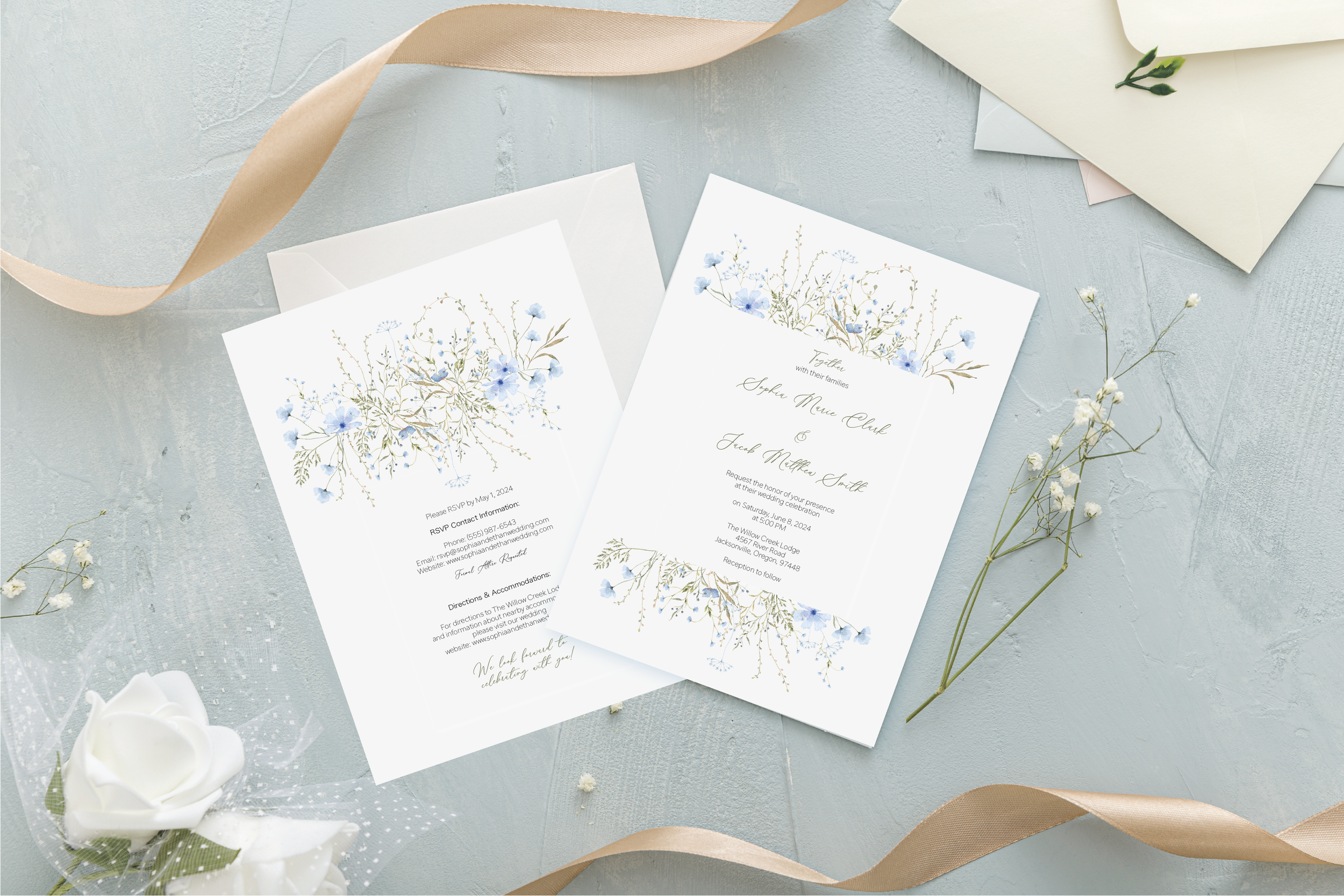 Wedding invitation cards with floral designs and light-colored embellishments on a textured surface, surrounded by ribbons and small white flowers.