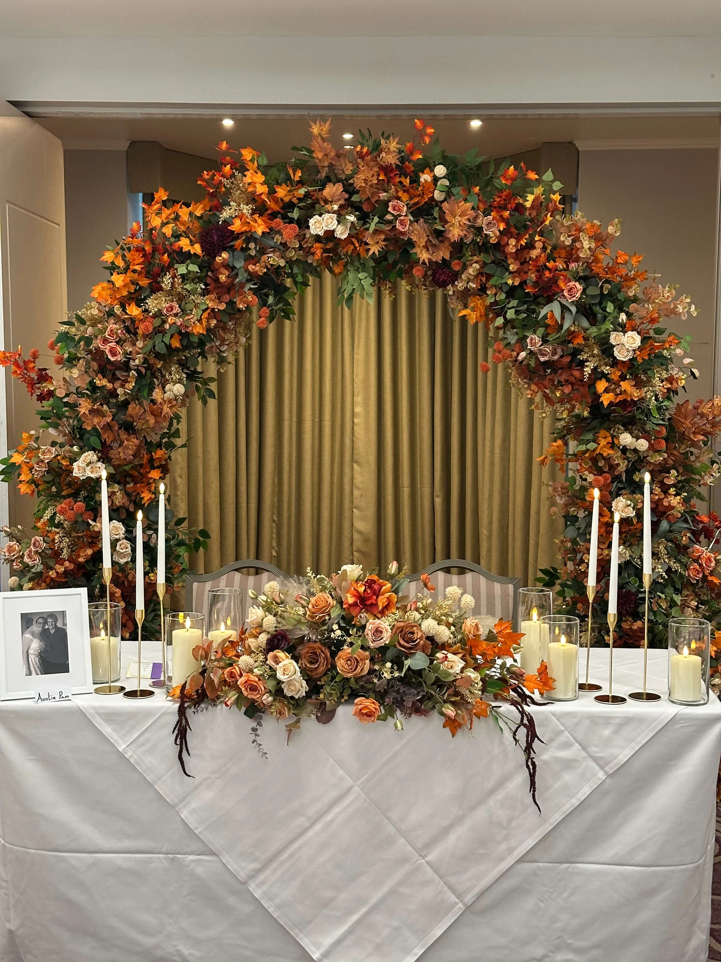  Luxury autumn wedding arch for hire,  featuring foliage, maple leaves and subtle floral accents. Premium faux design, styled and installed across Surrey.