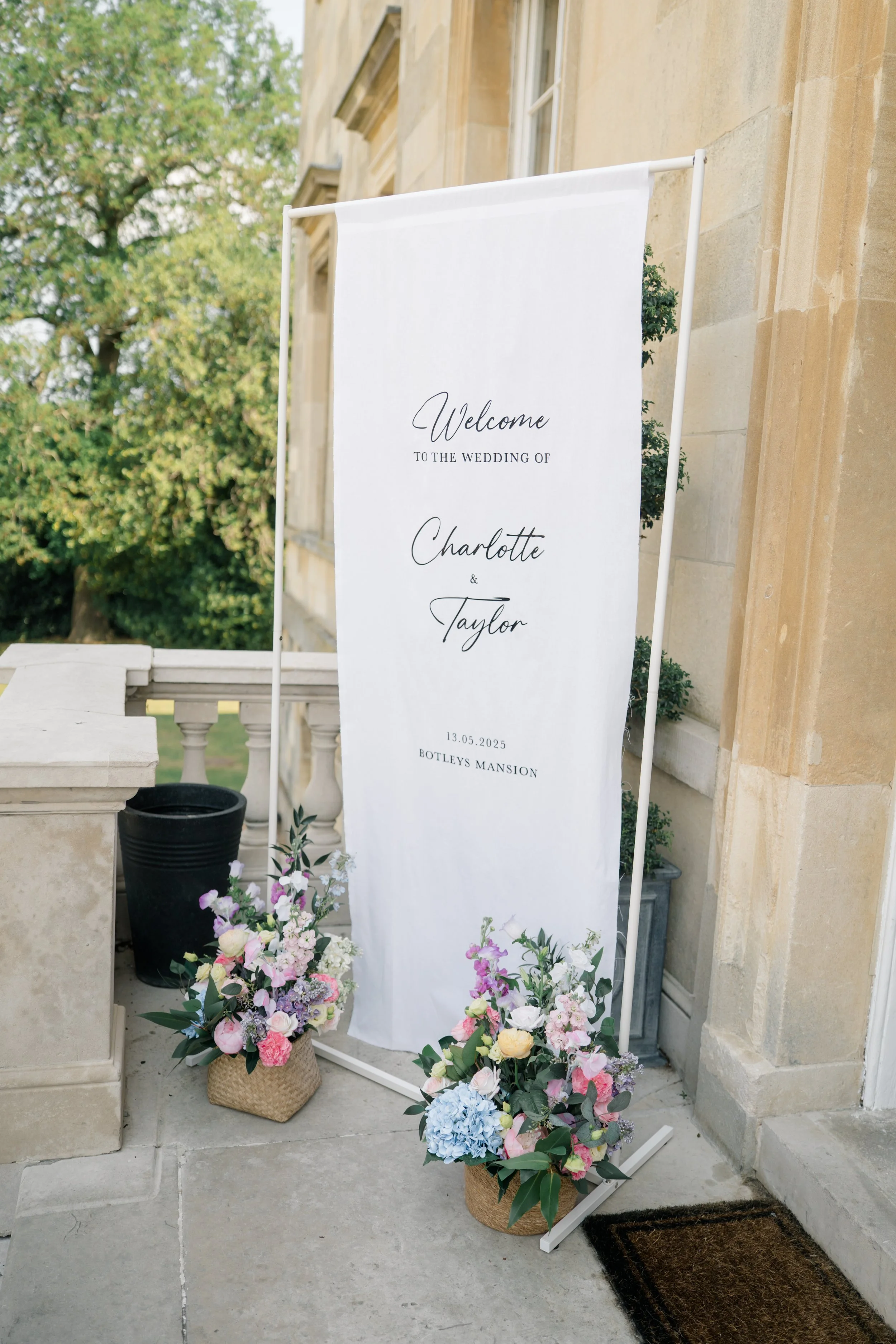 Wedding welcome sign for Charlotte and Taylor at Botleys Mansion, decorated with floral arrangements.