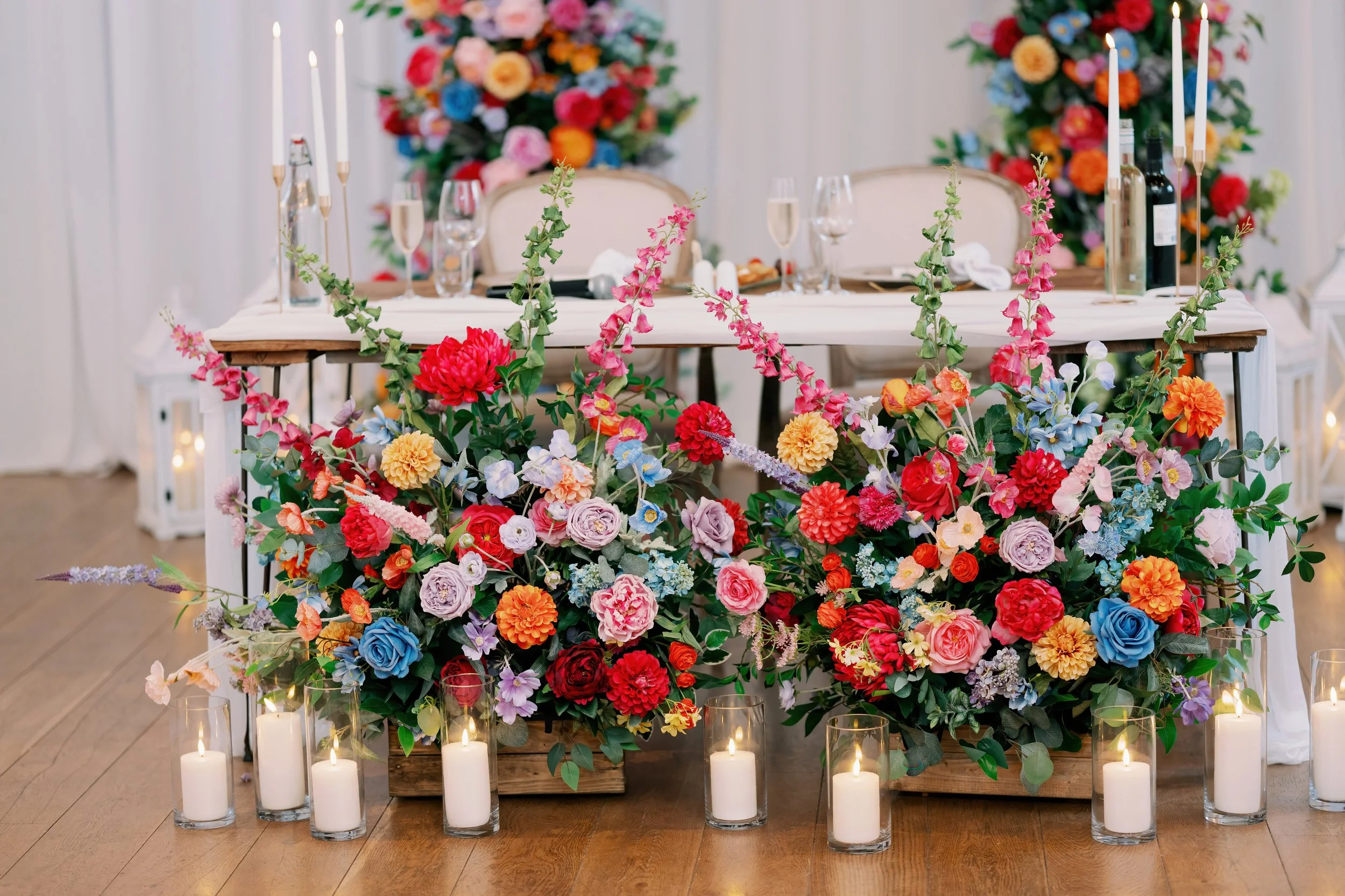 Wedding or event table decorated with large floral arrangements, candles, and elegant table settings.