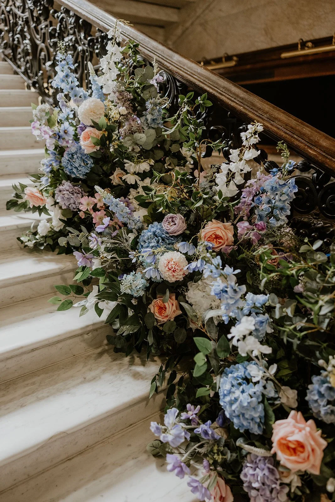 A floral arrangement with pink, blue, white, and purple flowers on a staircase railing.