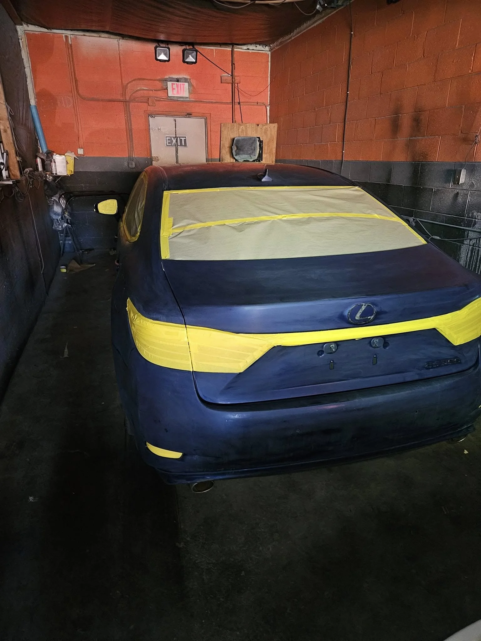Car with taped windows in garage being prepared for painting