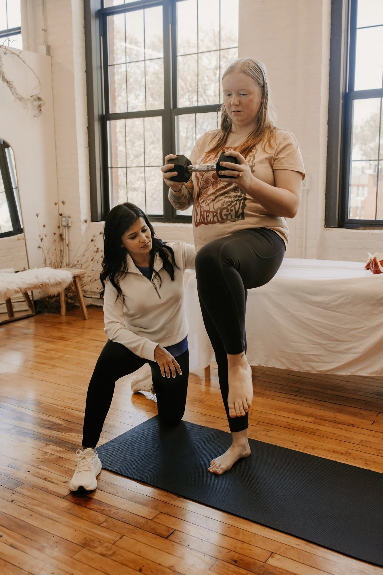 a pelvic floor physical therapist working with a patient on single leg stability training during a session
