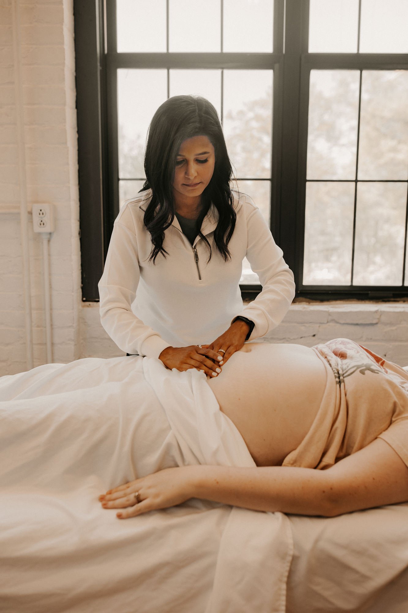 pelvic therapist palpating belly tissue for a patient who is postpartum.