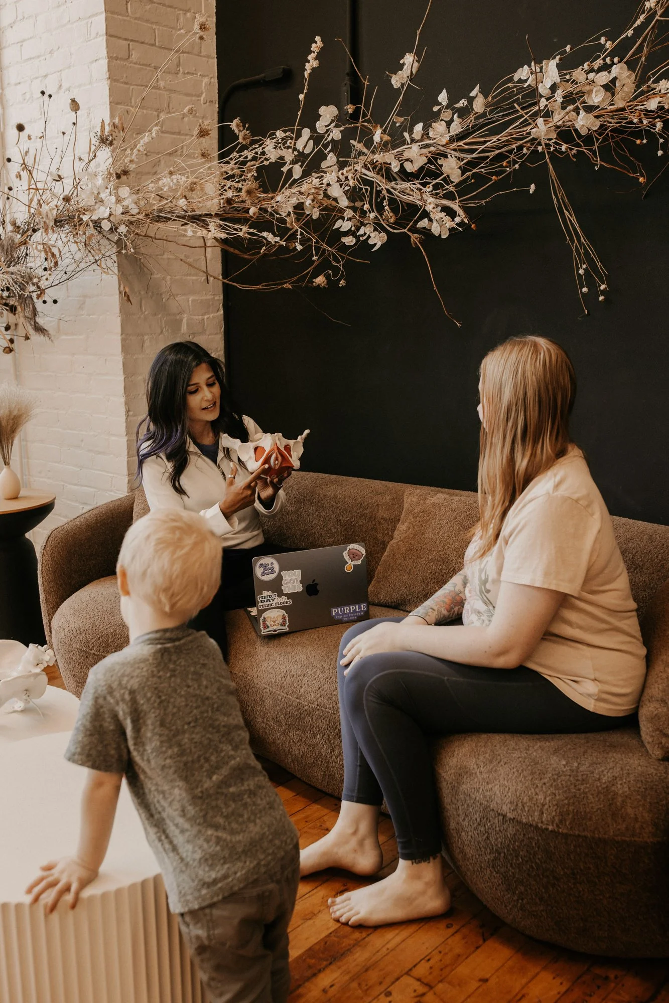 a pelvic therapist holding a pelvic model, talking to a patient about pelvic health therapy while sitting in the clinic