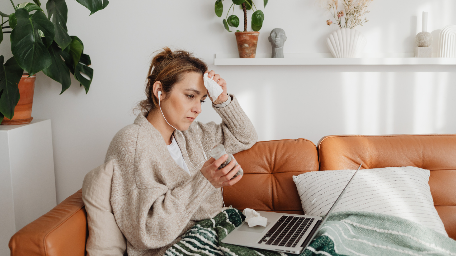 sick woman wiping brow with tissue