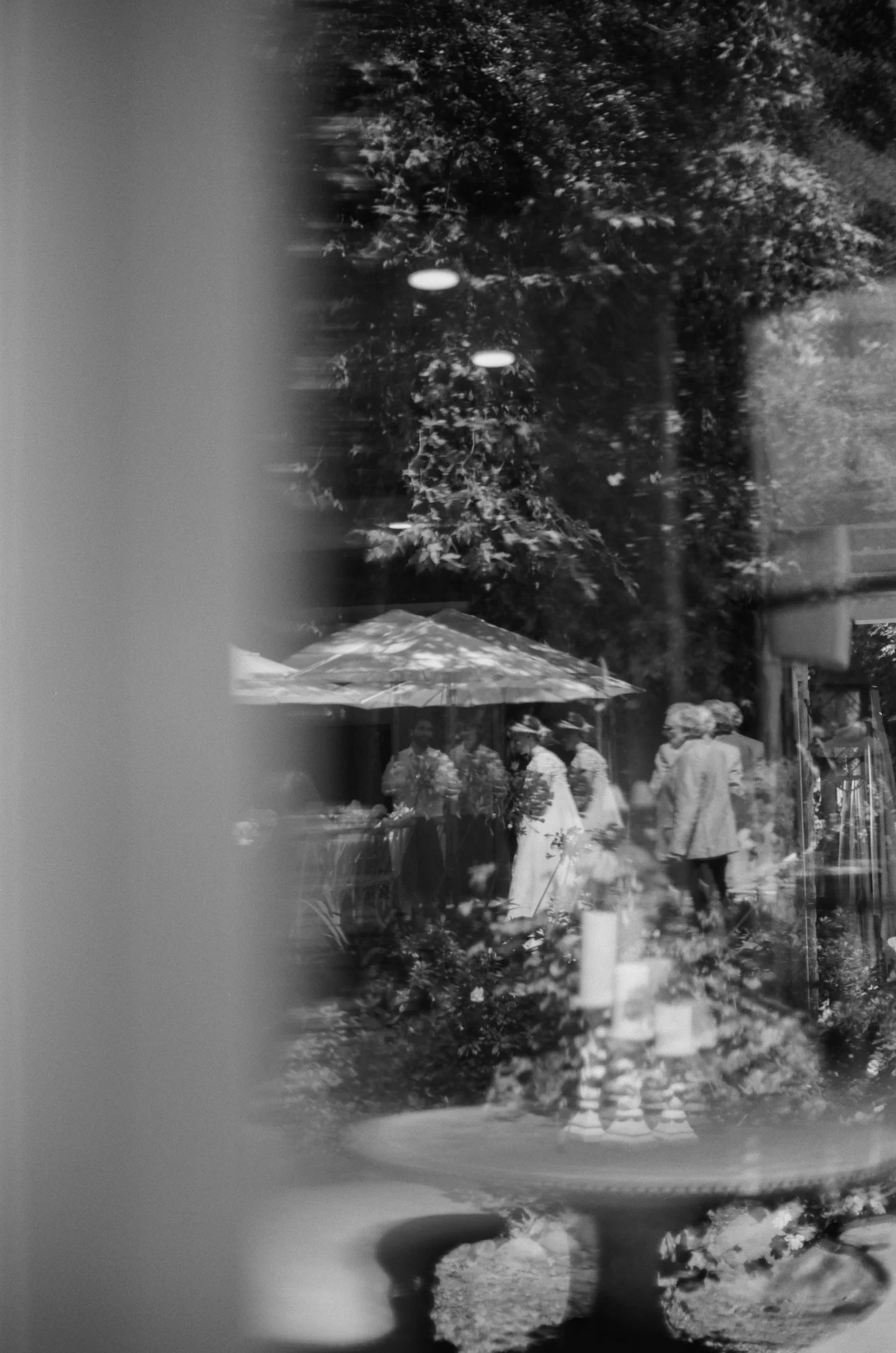 Black and white photo of a wedding ceremony under large trees.