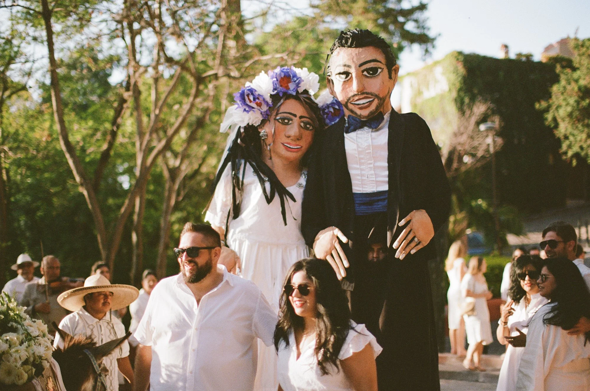 Bride and groom smiling with wedding guests in a garden setting.