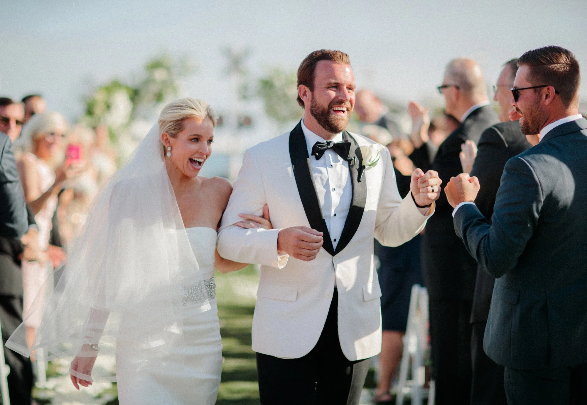 Bride and groom walking down the aisle smiling and celebrating after wedding ceremony at Rosewood Miramar Beach, photographed by Michael & Anna Costa