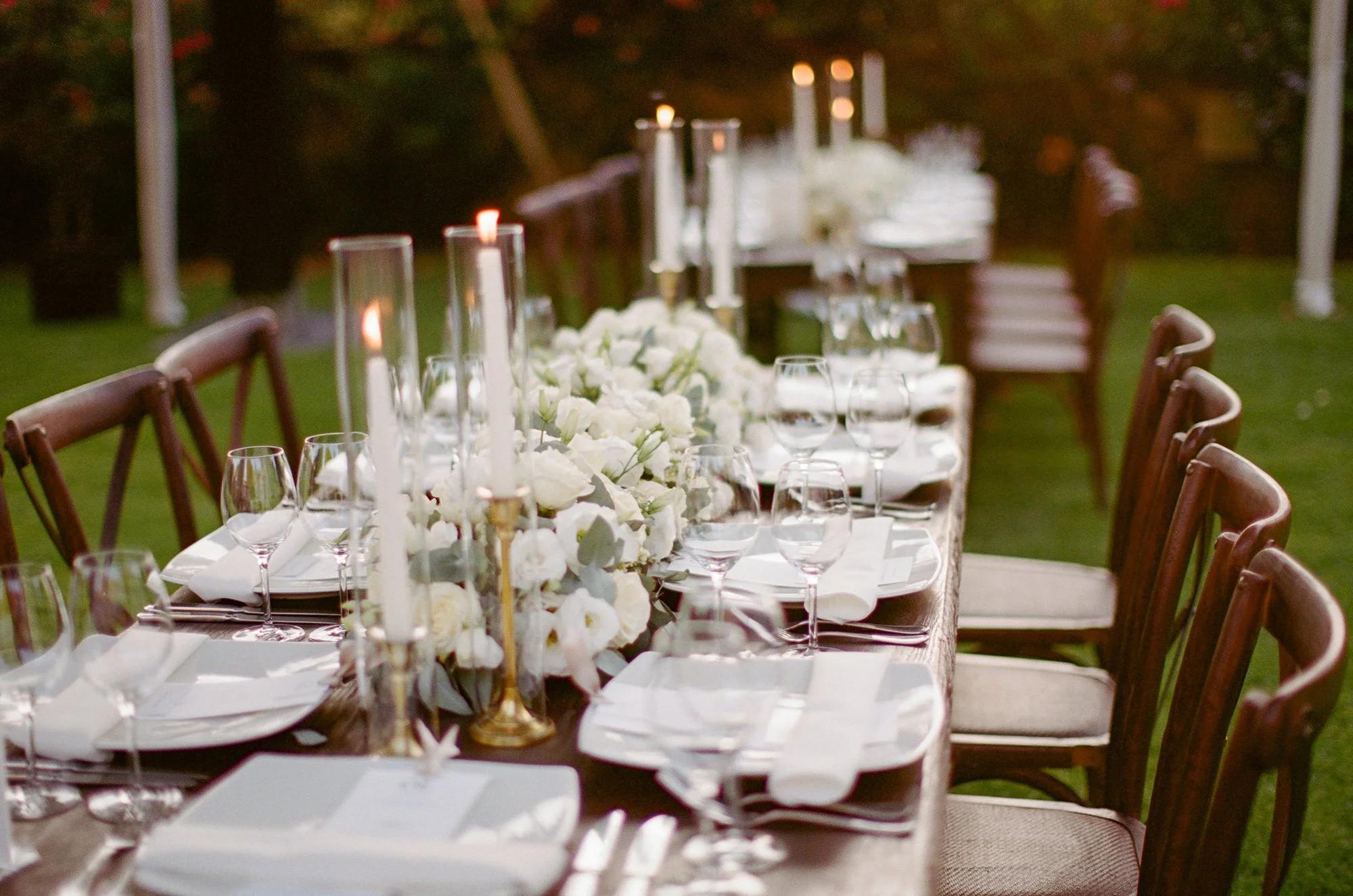 utdoor reception area with long tables, white linens, and floral centerpieces.