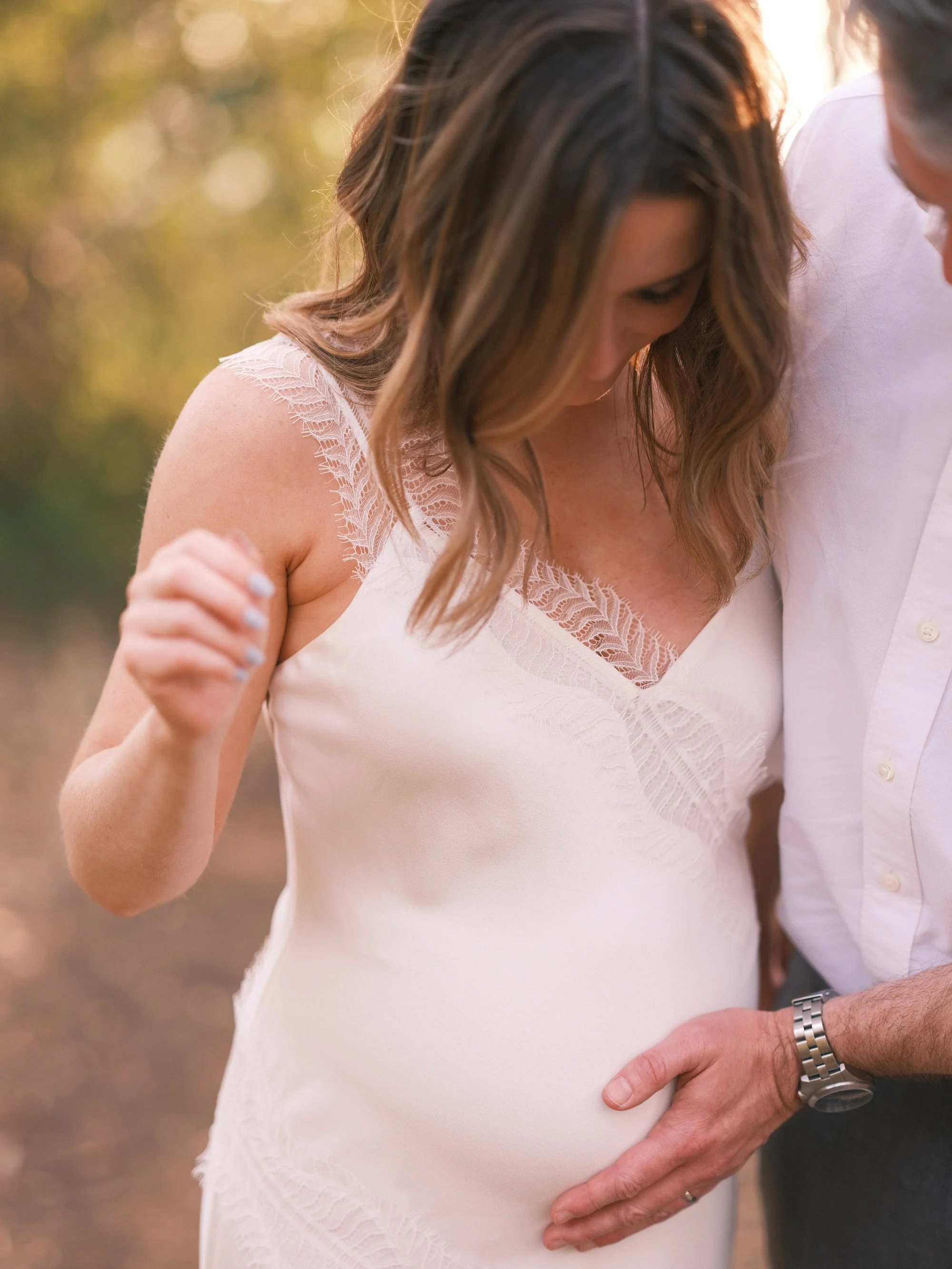 Bride in a white dress, close-up of her holding her necklace.