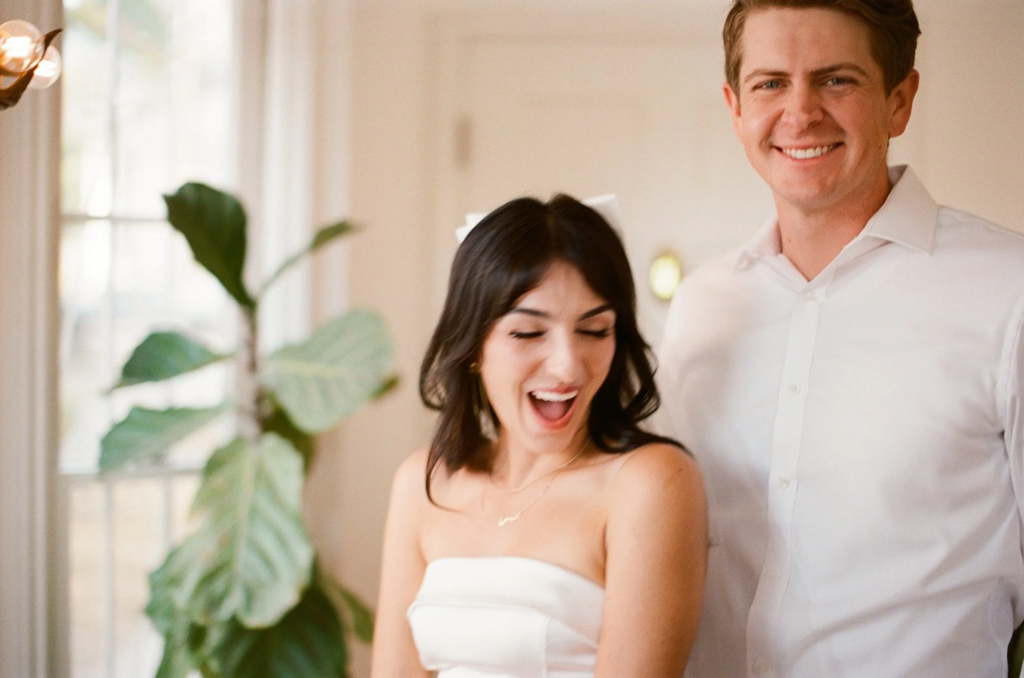 Woman in a white dress smiling at the camera indoors.
