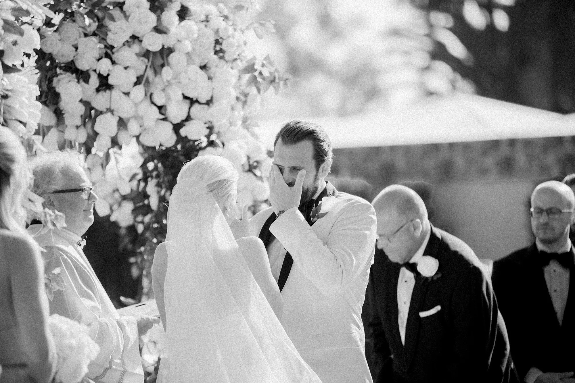 Bride and groom exchanging vows at outdoor wedding ceremony with officiant at Rosewood Miramar Beach, photographed by Michael & Anna Costa