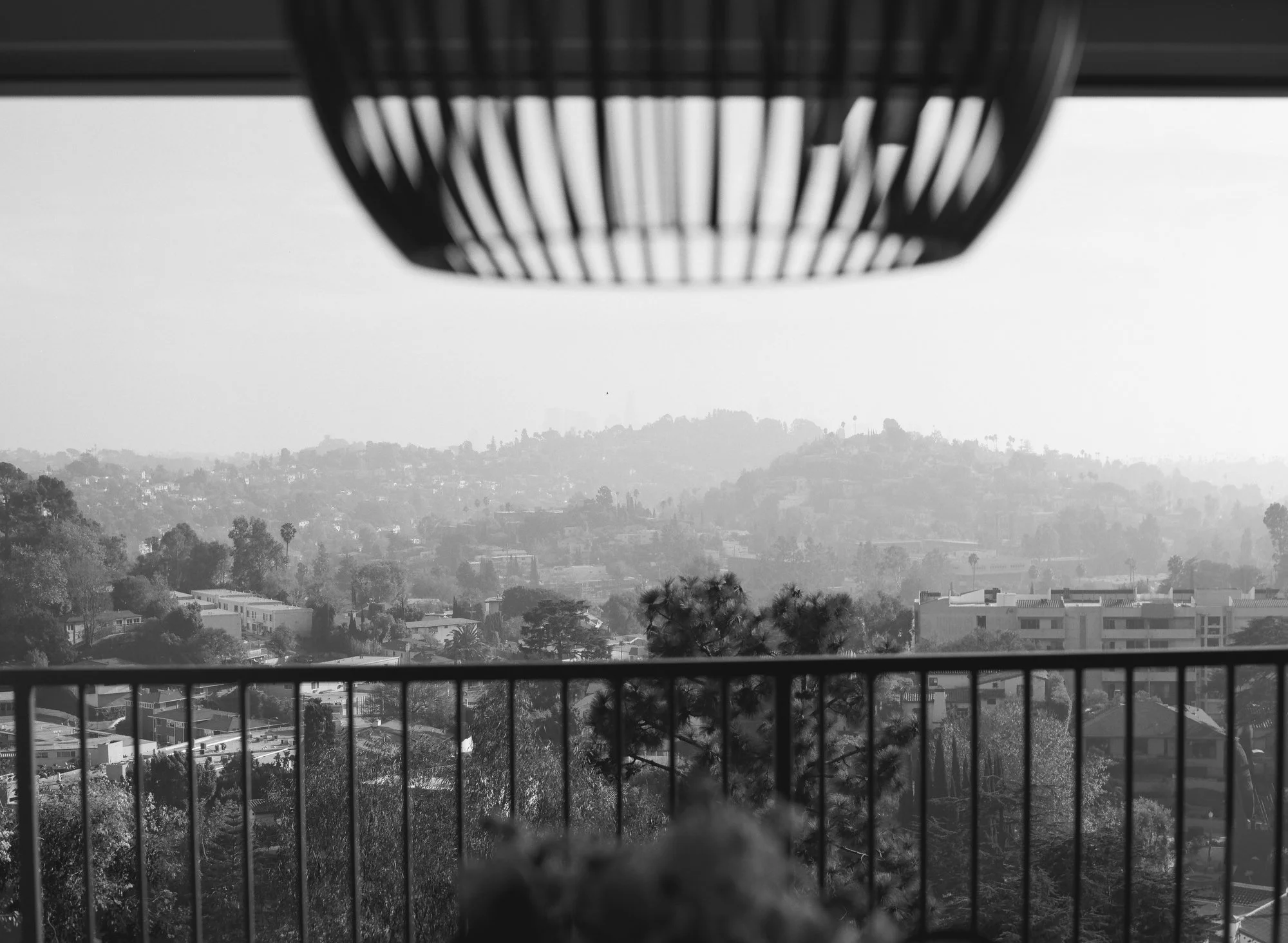 Black and white view of mountains and trees from a balcony.