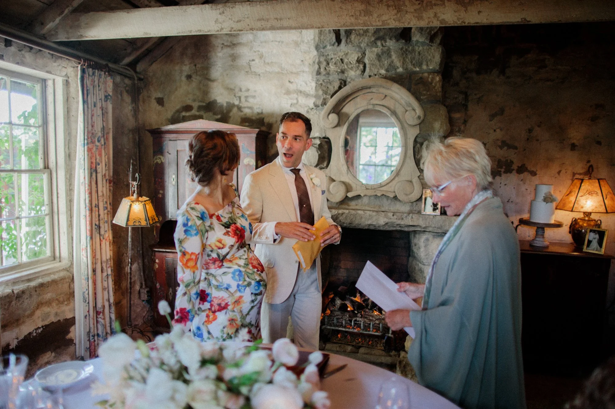 Black and white photo of bride and groom toasting with champagne at a rustic table.