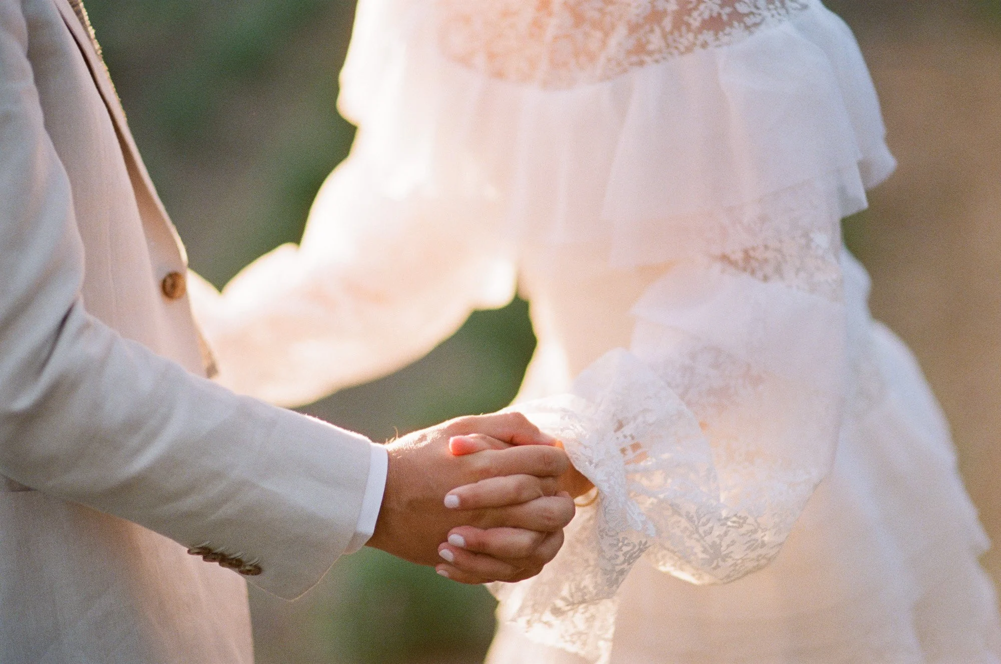 lose-up of couple holding hands, bride in white lace dress, at San Ysidro Ranch wedding, photographed by Michael & Anna Costa