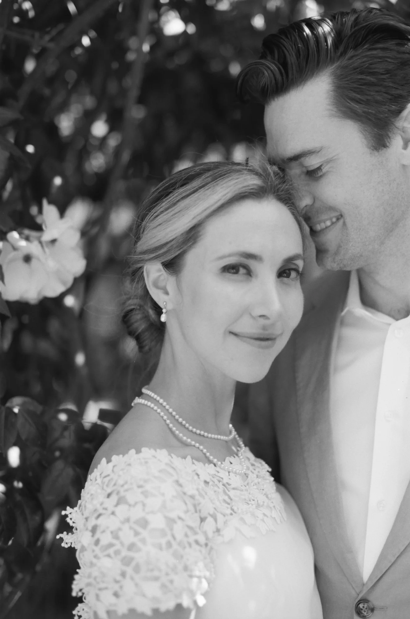 Bride smiling in a lace dress, close-up portrait with soft natural light.
