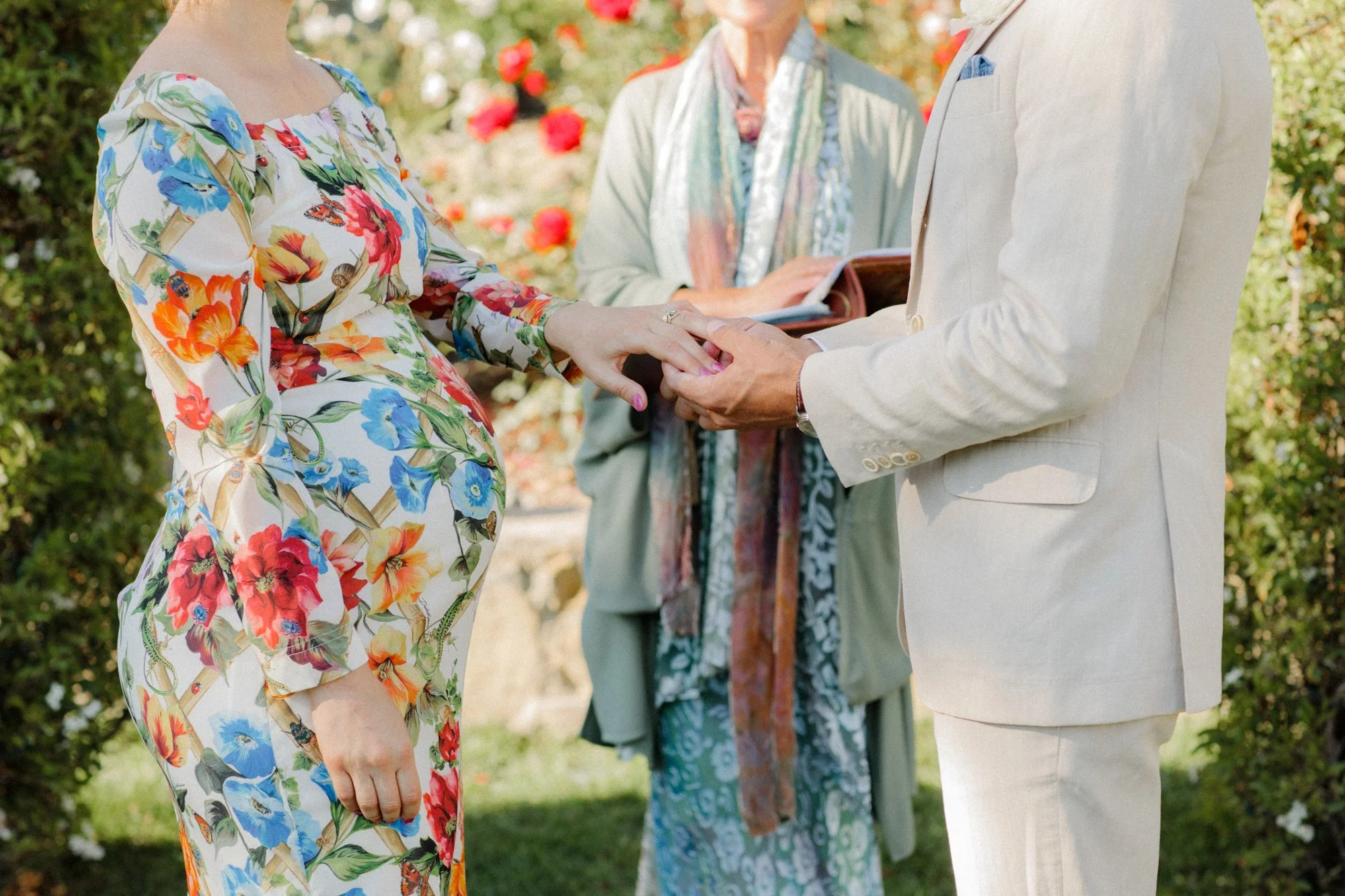 Couple holding hands during a wedding ceremony, with an officiant in the background.