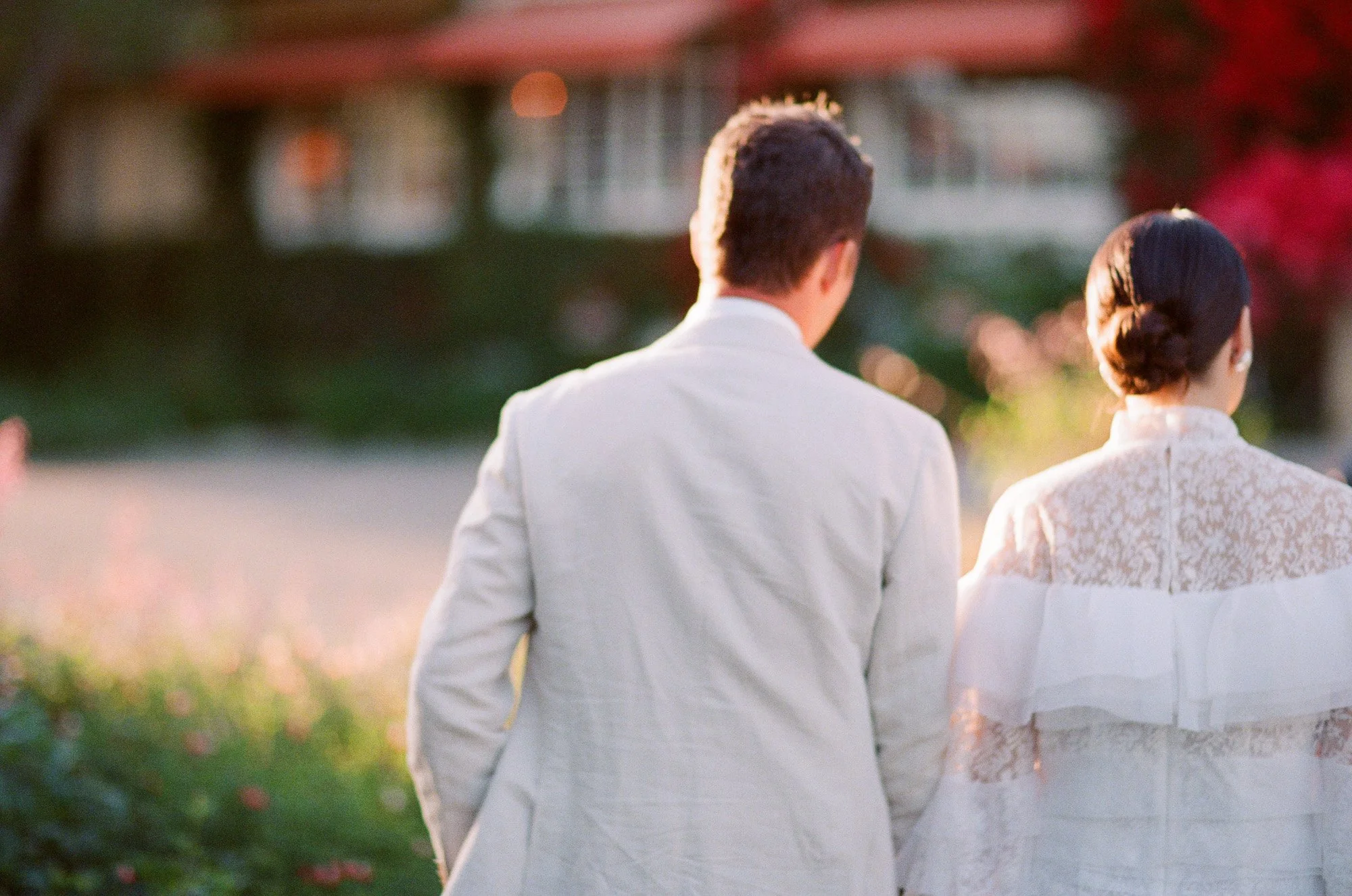 Bride and groom walking away together outdoors at San Ysidro Ranch wedding, photographed by Michael & Anna Costa